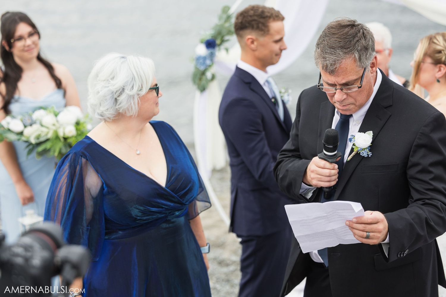 Wedding guests and family members gather around during an outdoor ceremony.