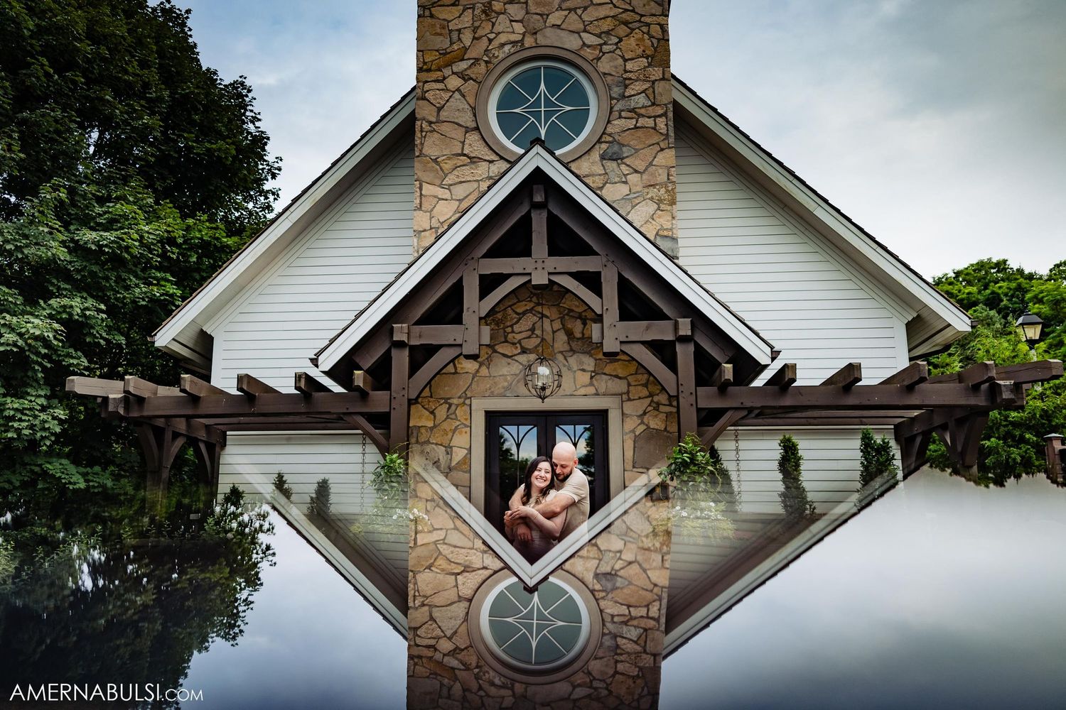 Chapel with stone facade and stained glass window reflected in mirror-like surface.