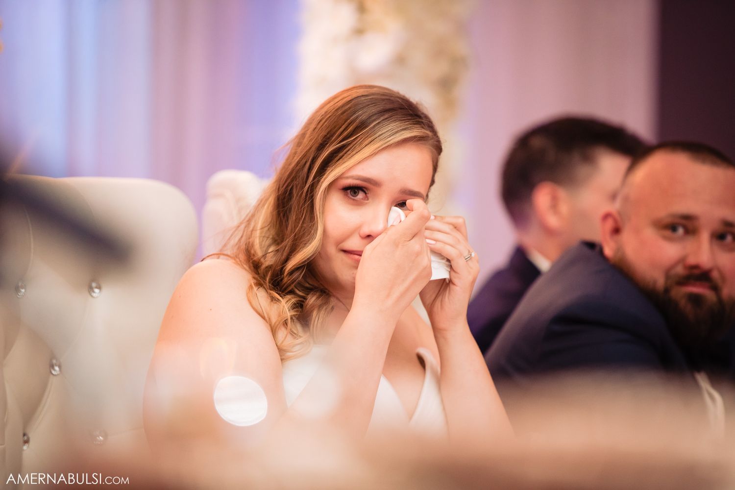 Soft-focus wedding ceremony moments captured in warm pink lighting.