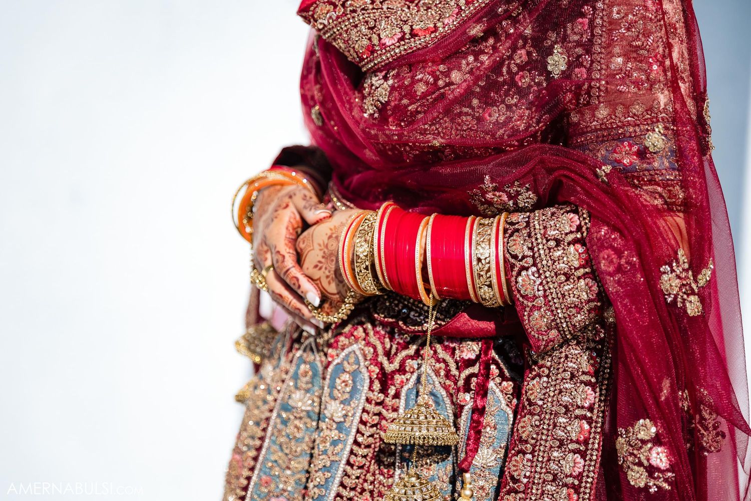 Close-up detail of traditional Indian bridal jewelry and red wedding attire.
