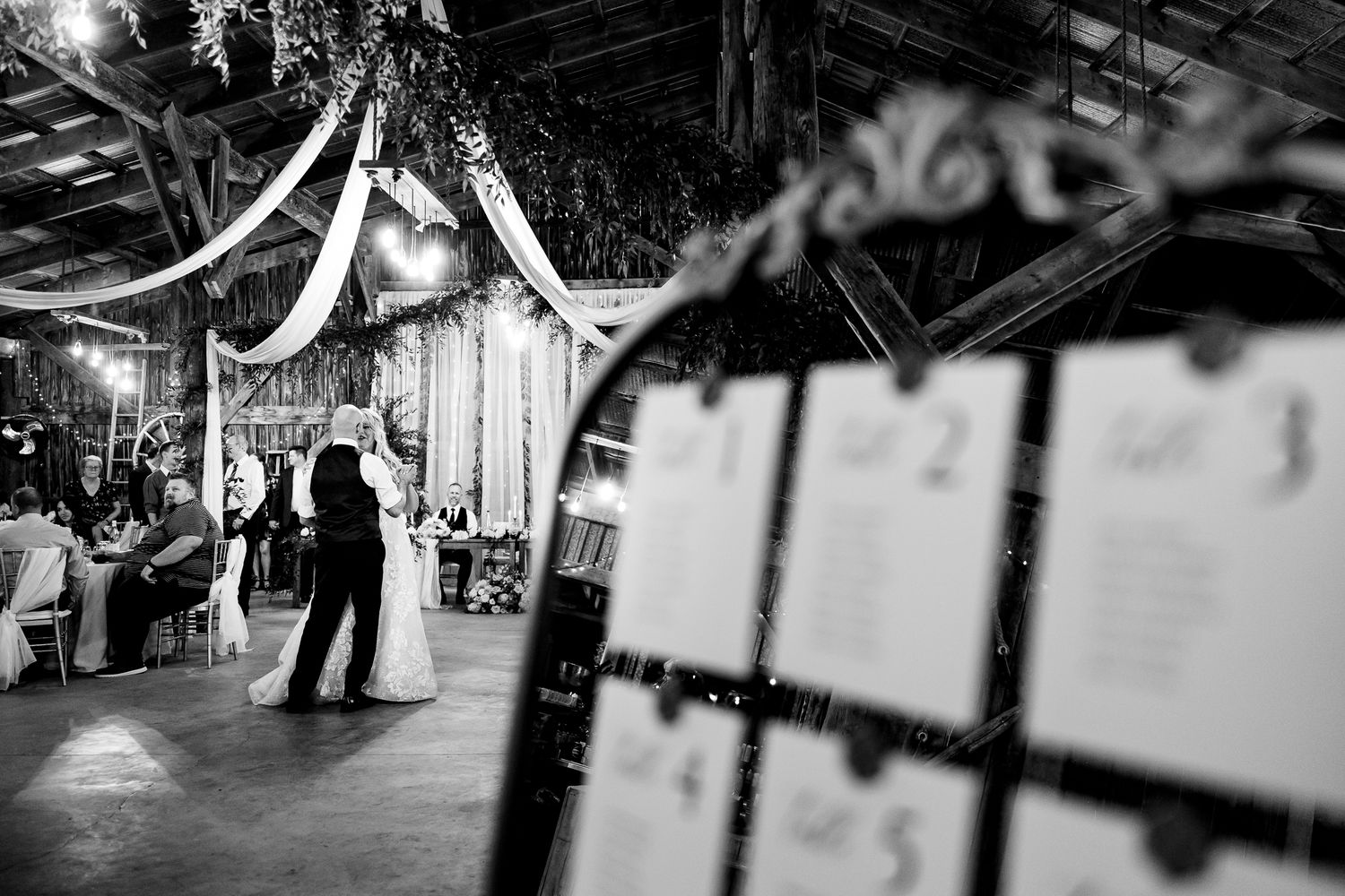 Black and white shot of couples slow dancing at an elegant reception venue.