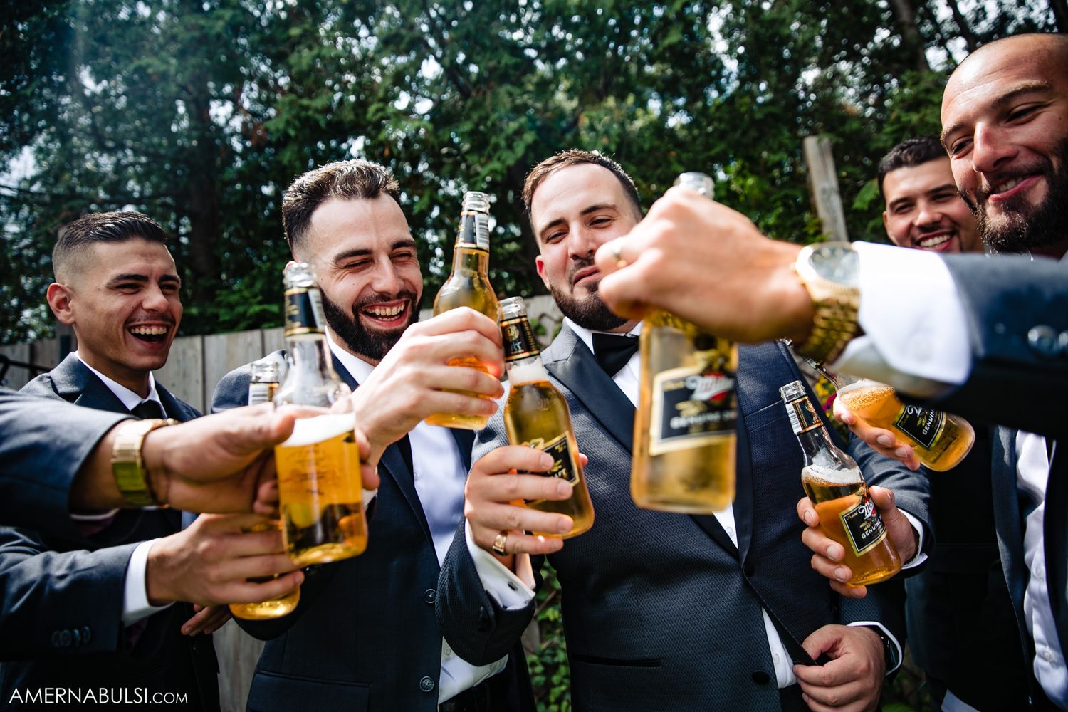 Wedding party guests toasting and clinking beer glasses together in celebration.