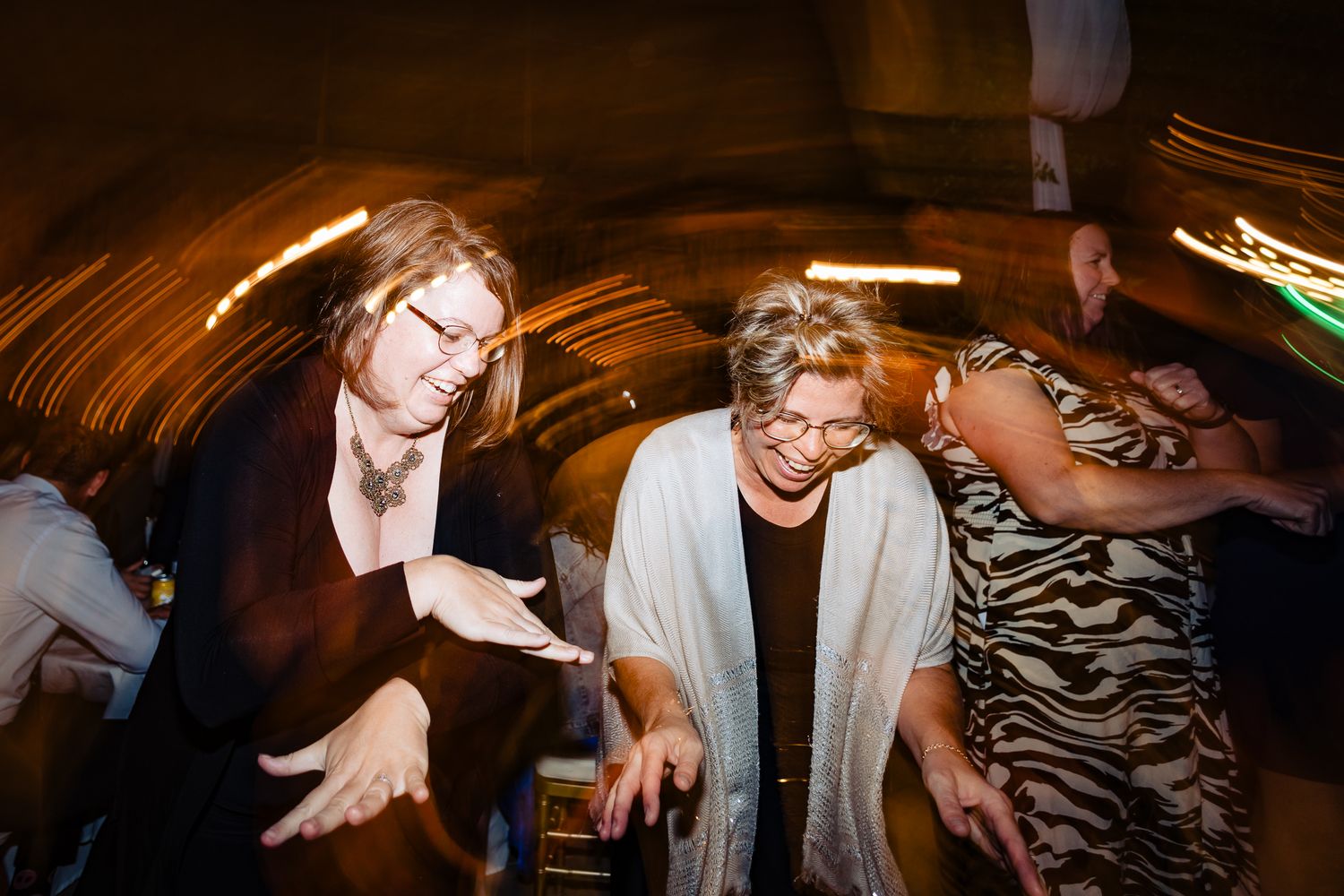 Dance floor filled with energy as wedding guests move to the music in atmospheric lighting.
