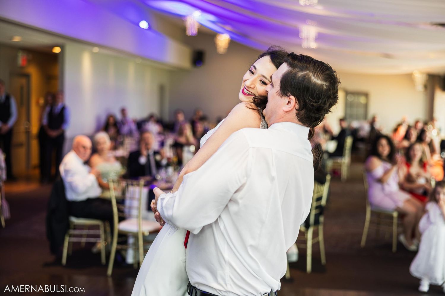Romantic dance moment captured during wedding reception with guests watching.