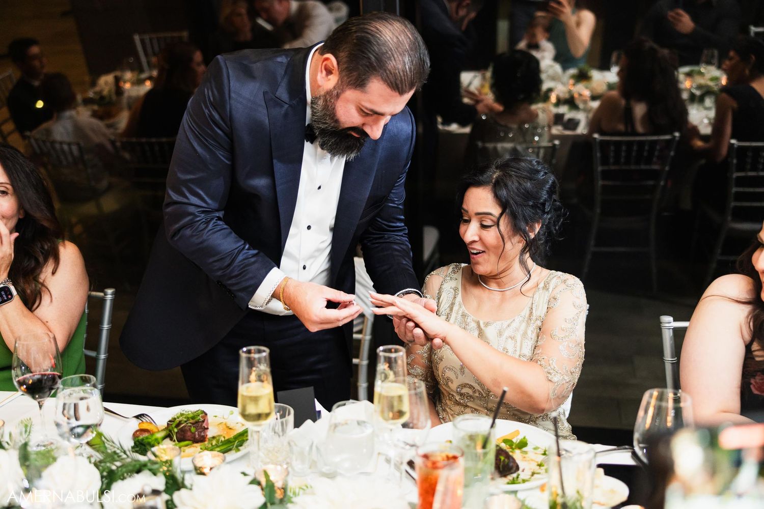 Couple exchanges gifts or notes during reception dinner at decorated table.