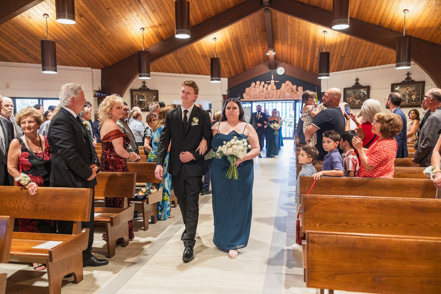 Newlyweds walk back down the church aisle smiling as guests celebrate their wedding ceremony.