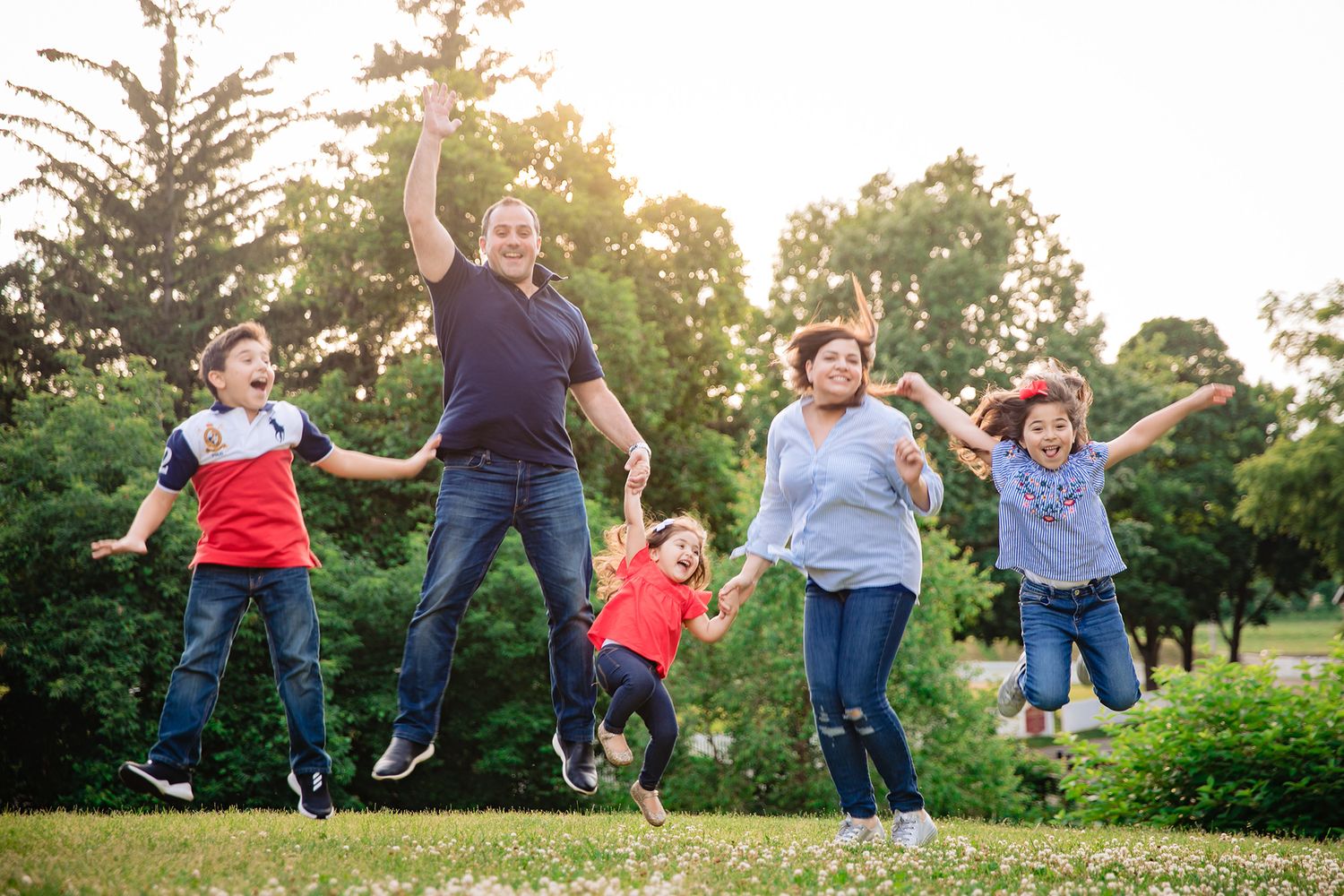 Group of friends jumping joyfully together in a park during golden hour sunset.