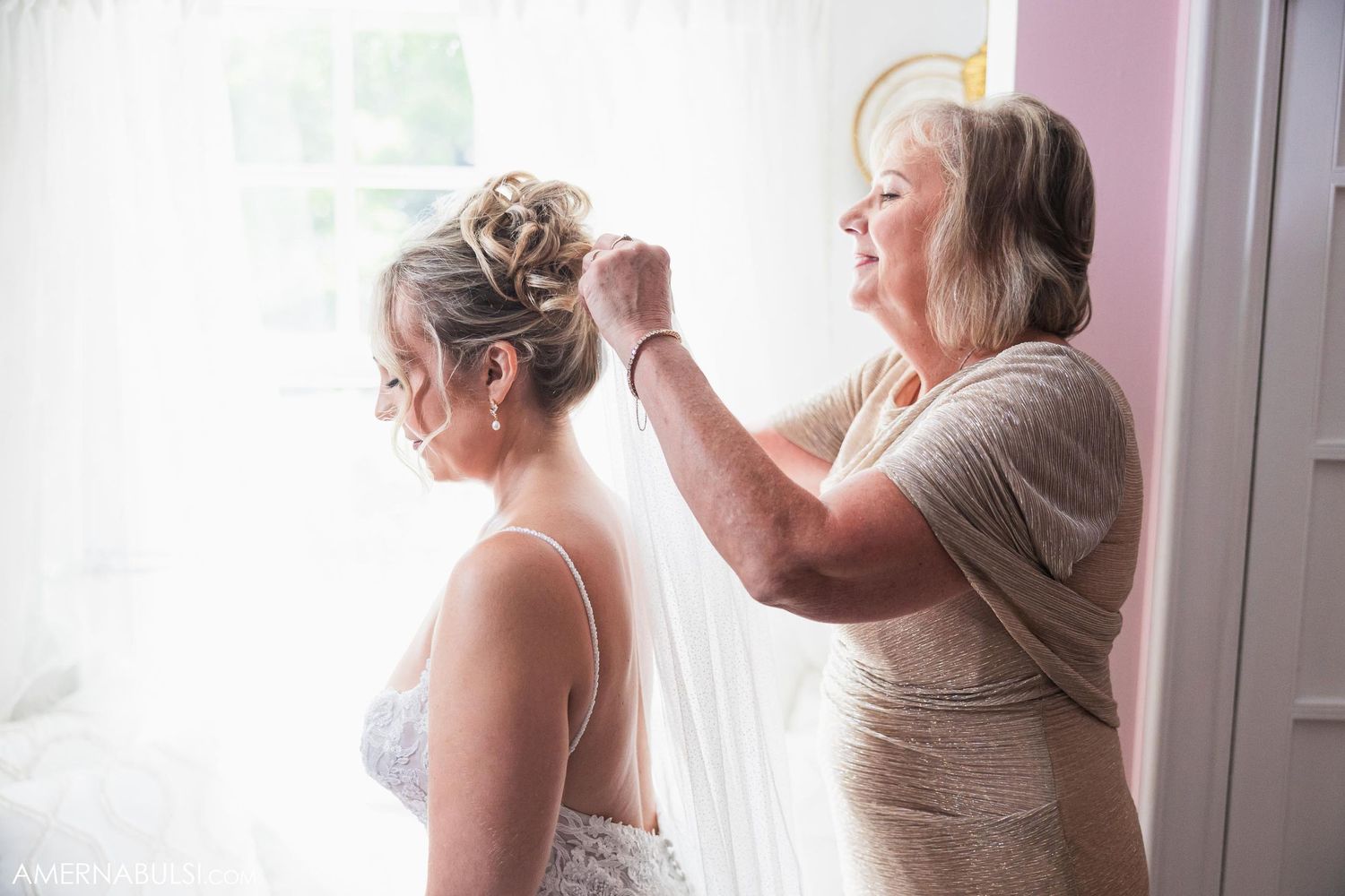Getting ready moment during wedding day preparations by window light.
