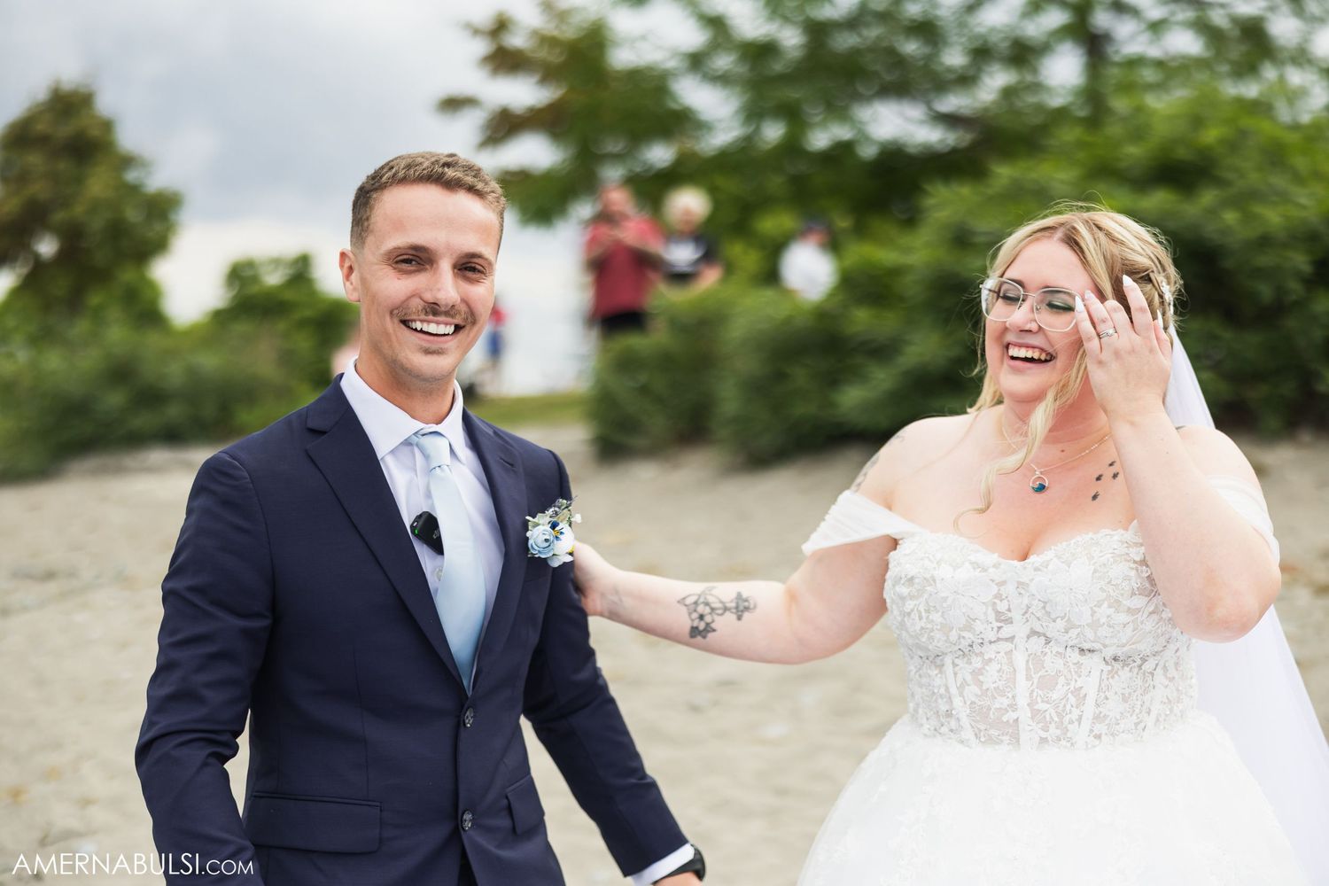 A couple shares a joyful moment on a beach during their wedding celebration.