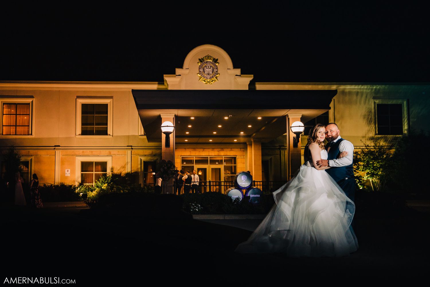 Romantic nighttime portrait outside an illuminated venue with elegant architecture.