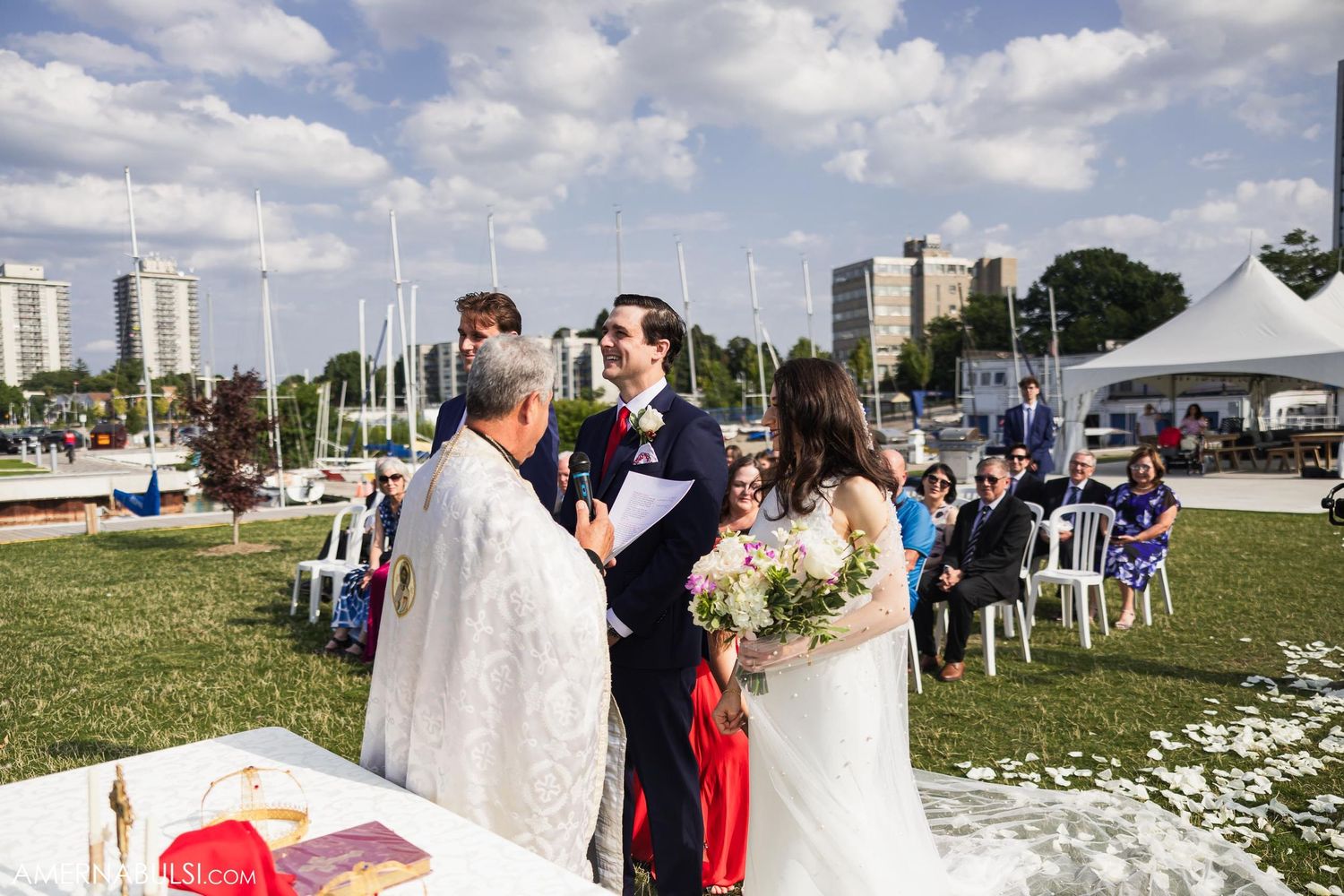 An outdoor wedding ceremony with a waterfront view and city skyline in the background.