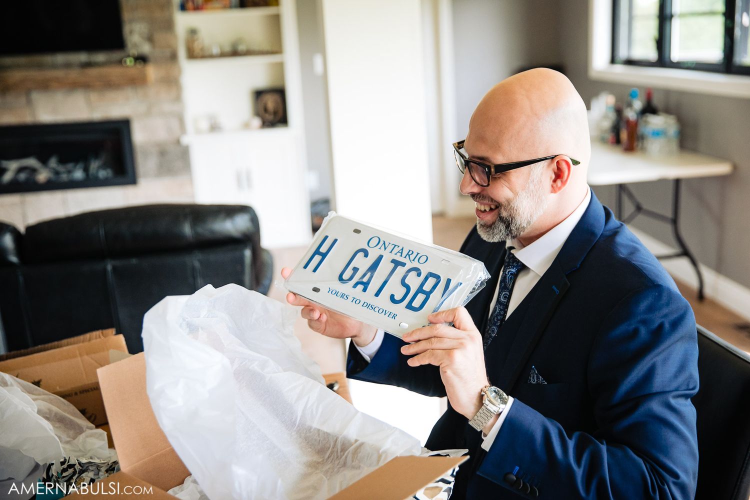 Men in formal attire sitting together opening gifts during pre-wedding celebrations.