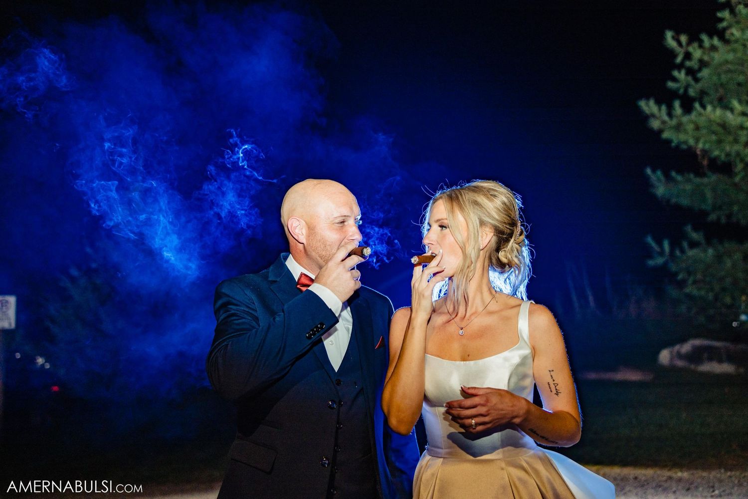 Evening outdoor wedding moment with blue smoke effects creating a dramatic atmosphere.