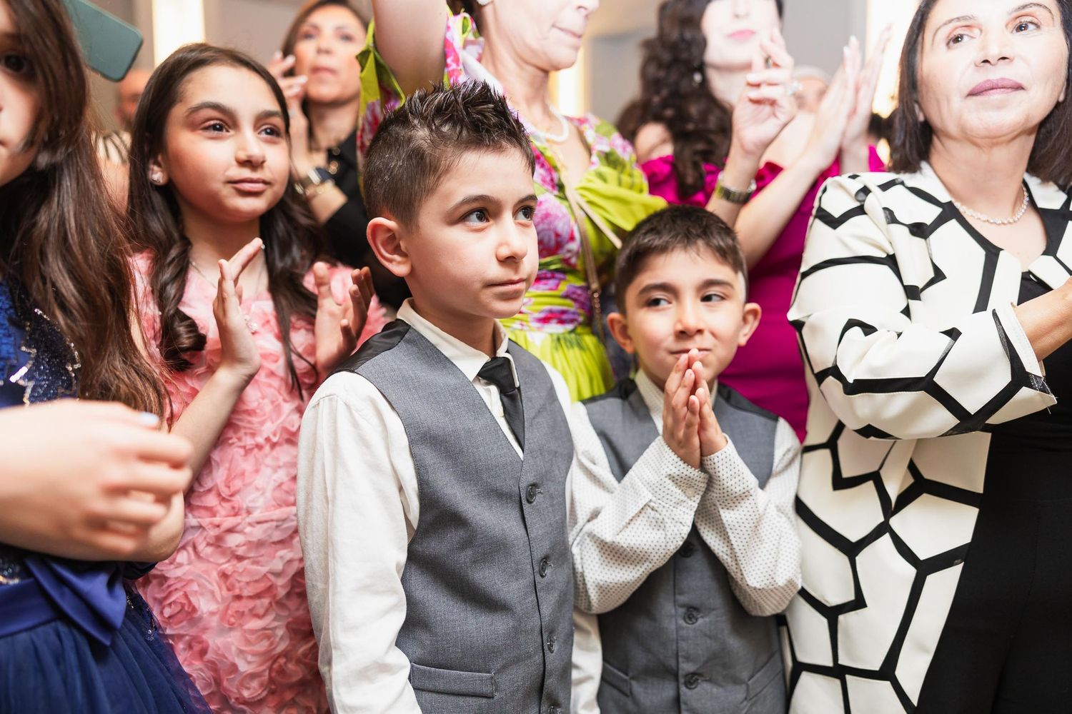 Young attendees watching and clapping during wedding celebration.