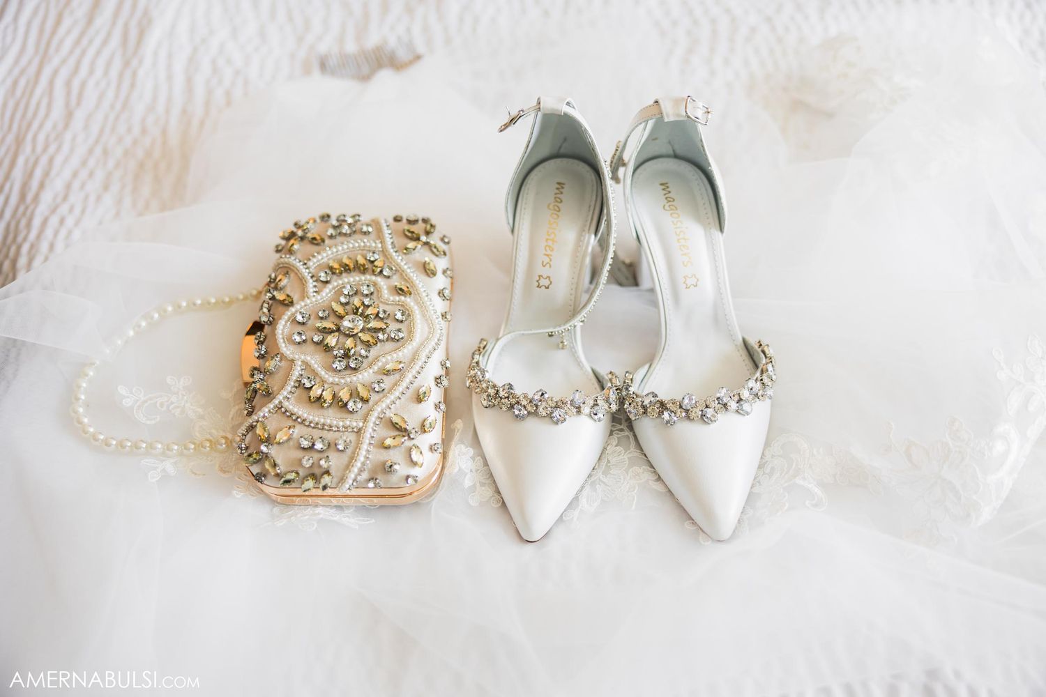 White bridal shoes and ornate clutch purse displayed on textured fabric.