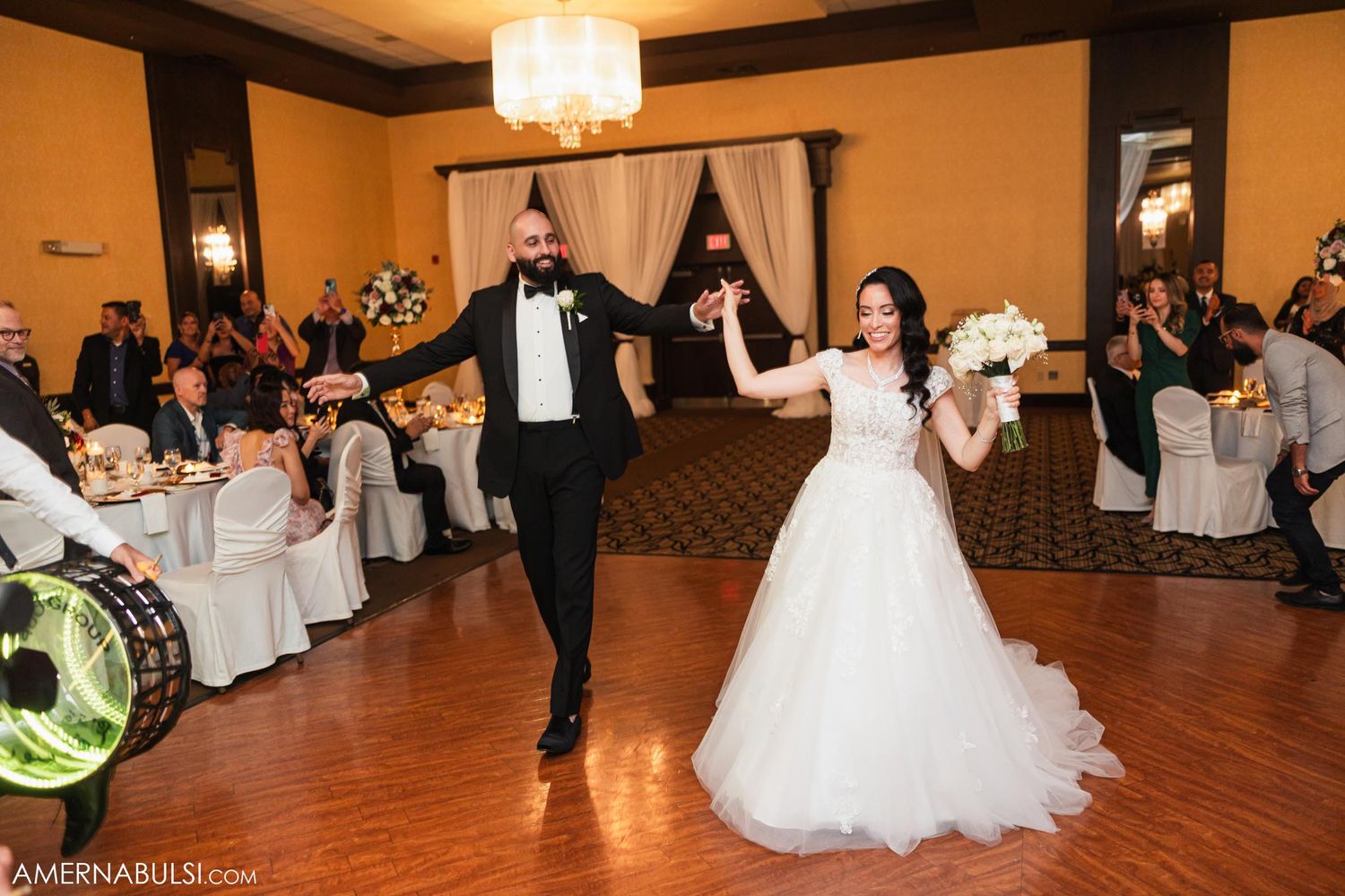A newlywed couple dancing together on a wooden floor during their reception celebration.
