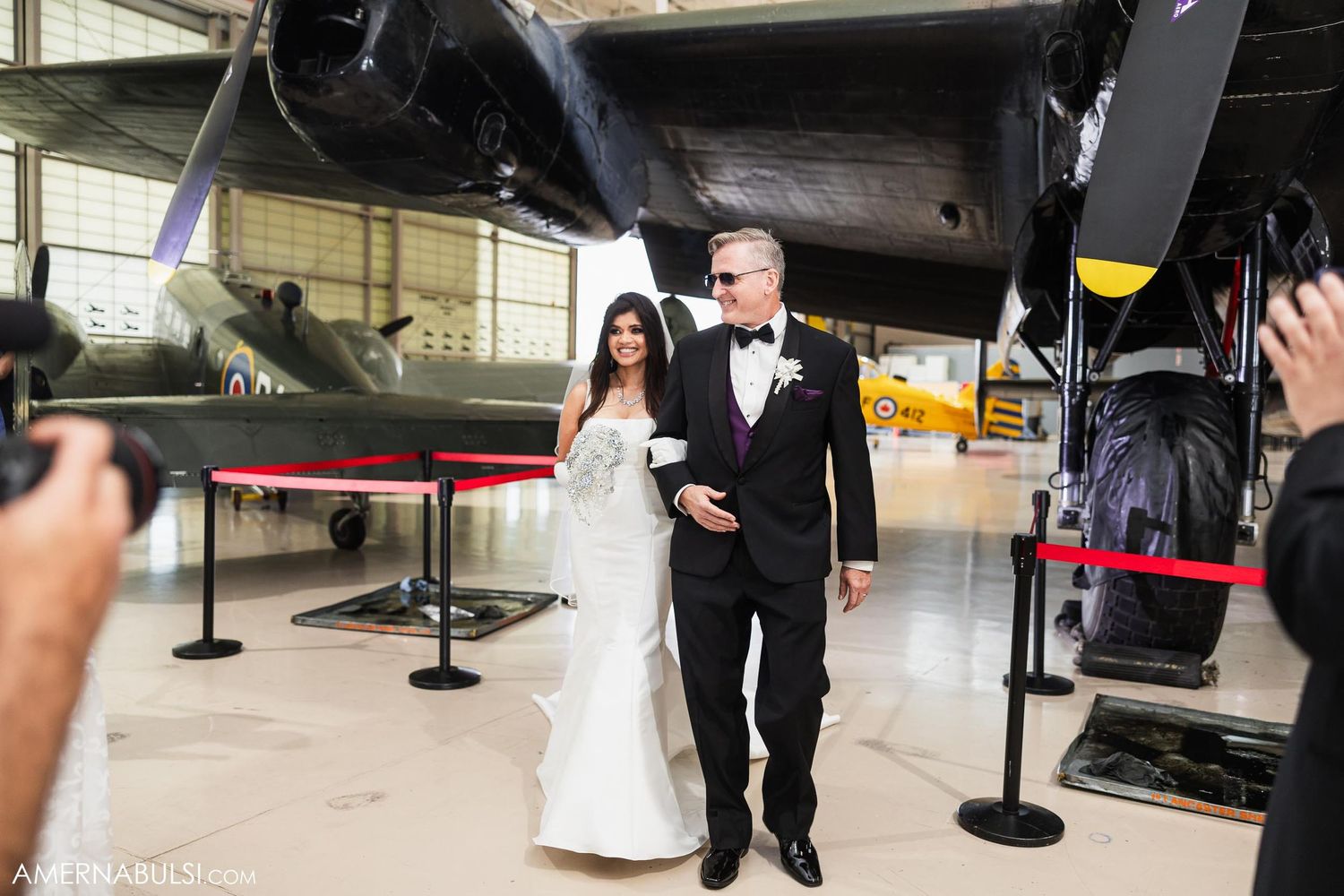 Couple walks together during wedding ceremony in vintage aircraft museum.