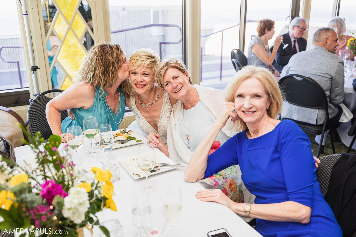 Guests enjoying a celebratory meal at an upscale restaurant with floral centerpieces.
