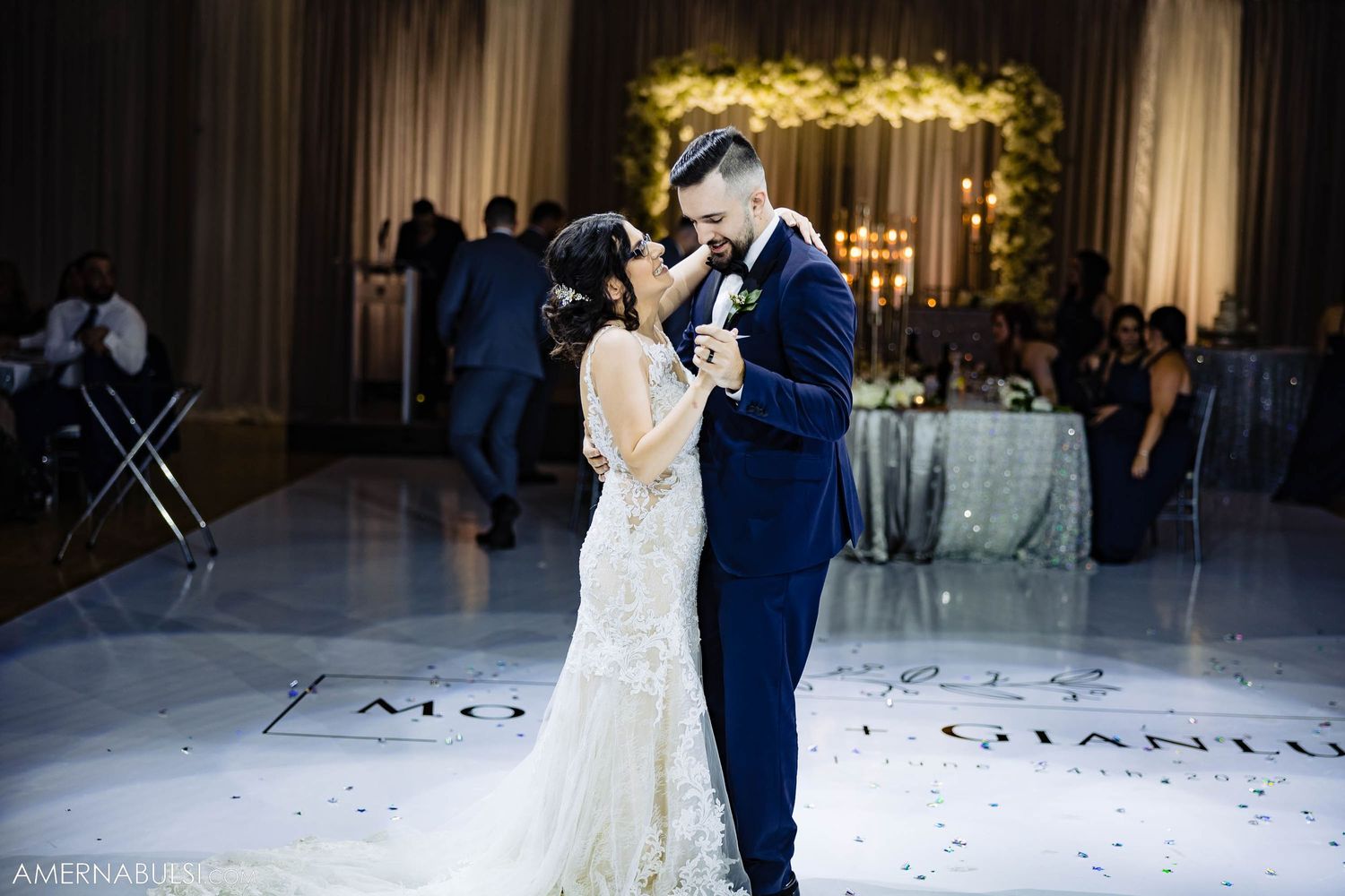 Elegant wedding couple sharing an intimate slow dance under dimmed lights at their reception.