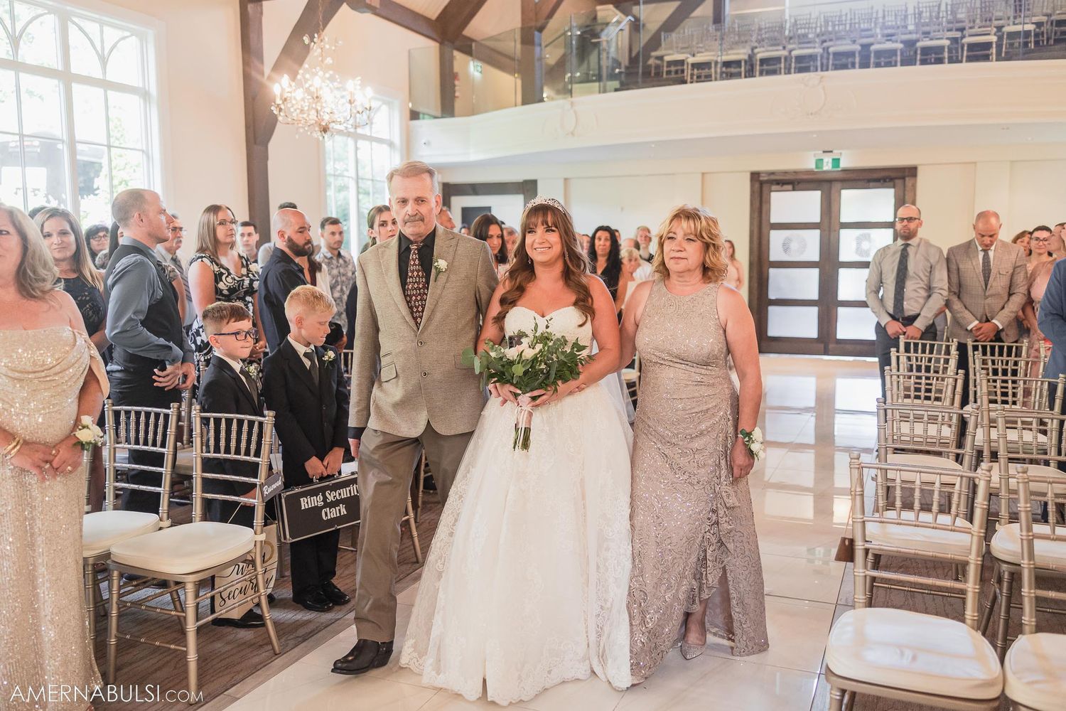 Wedding ceremony in progress inside bright chapel with exposed wooden beams and white chairs.