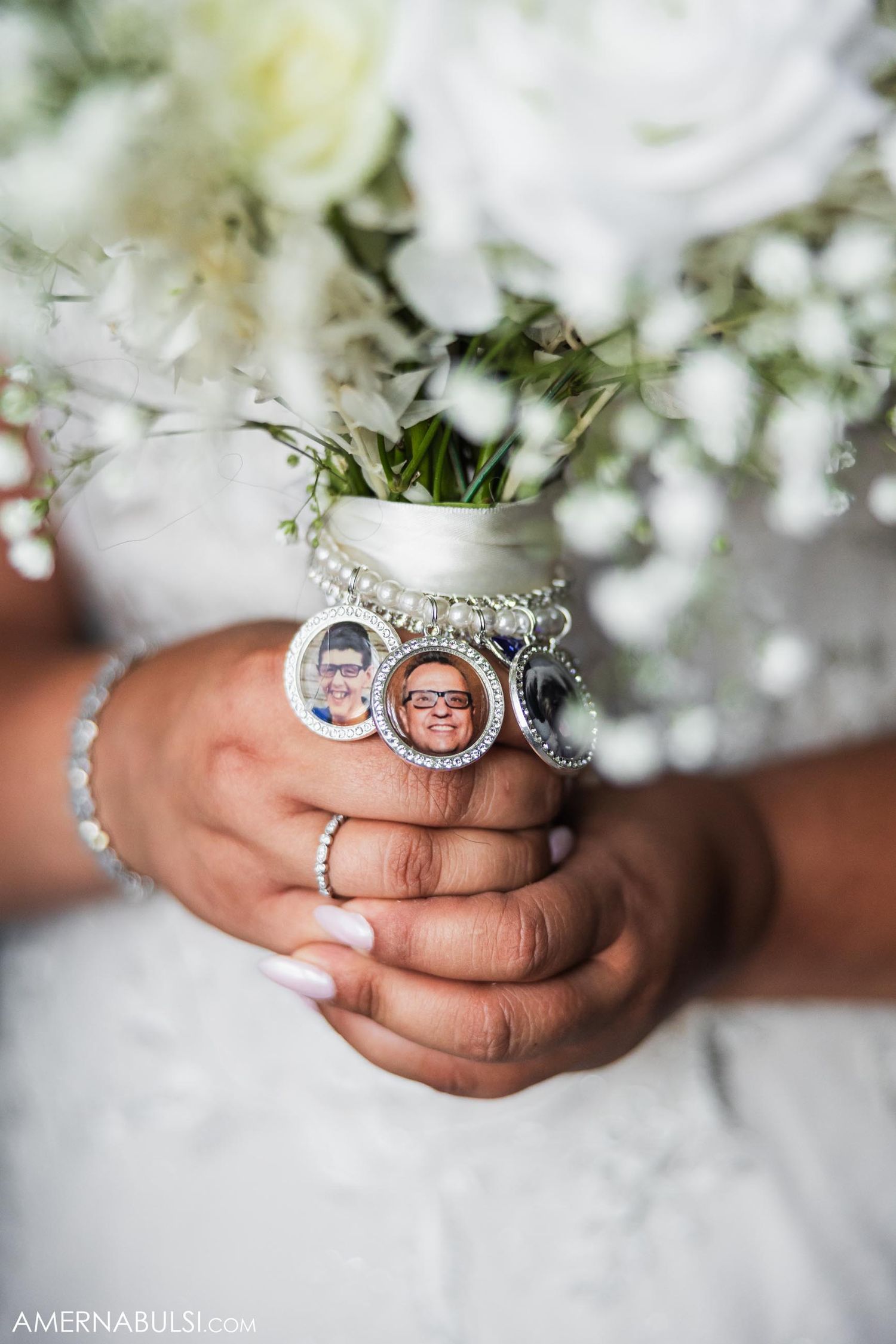 Close-up of hands holding white bouquet with memorial photo charms attached.