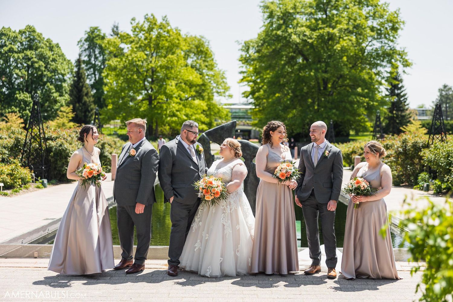 Wedding party lined up for formal photo in garden with bridesmaids in dusty rose dresses.