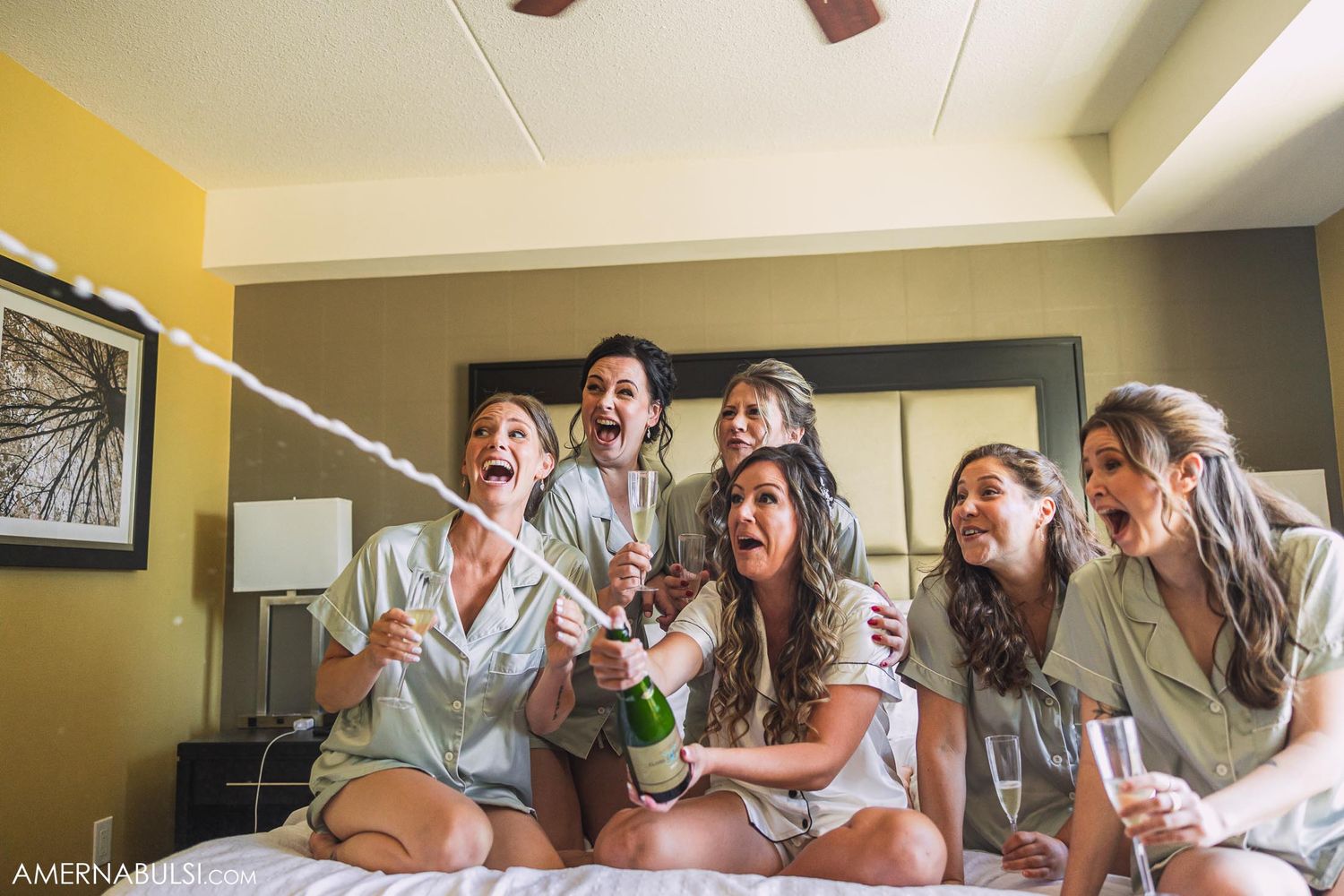 Friends having fun and laughing while celebrating with drinks in matching robes.