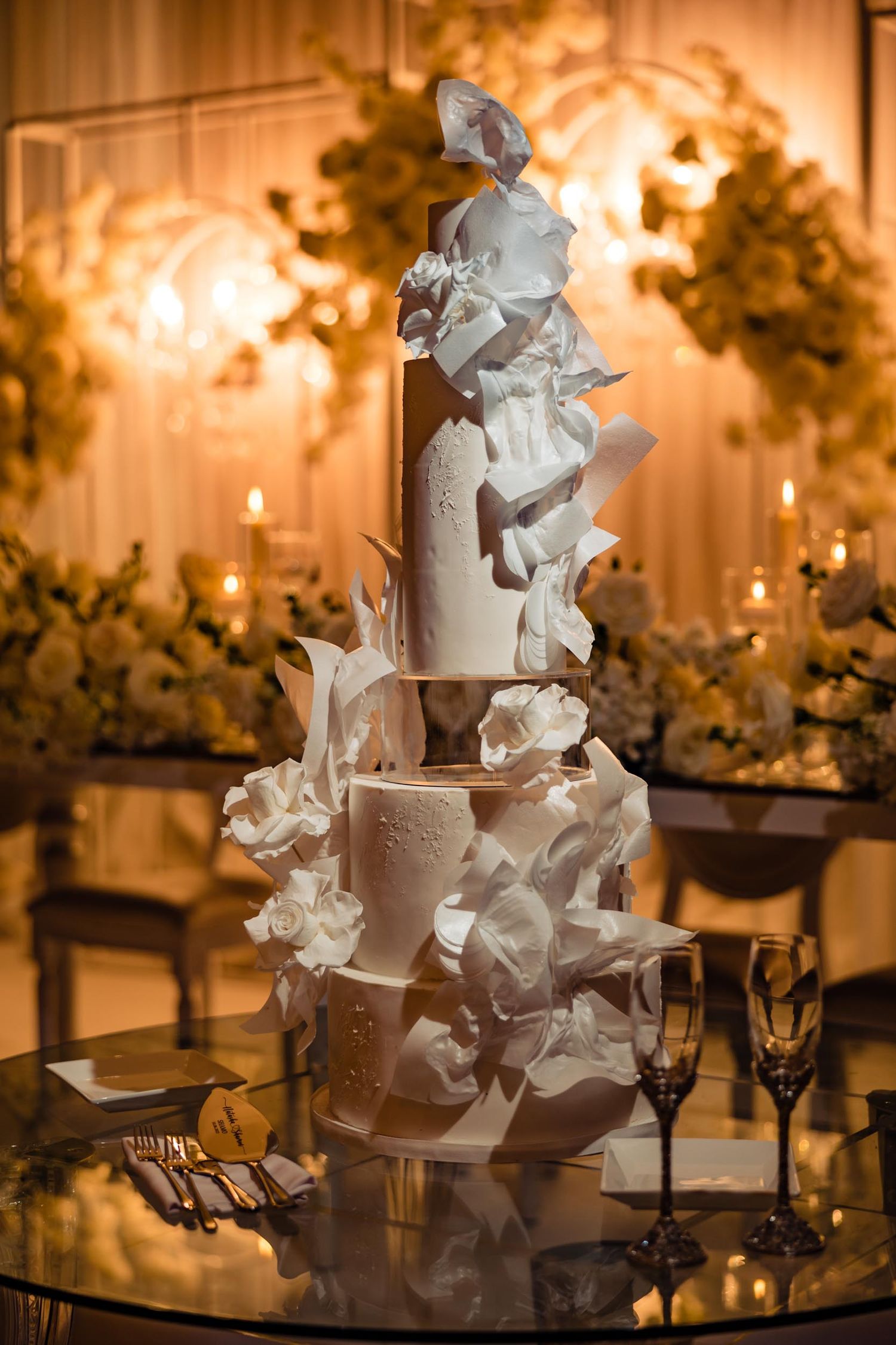 Elegant white wedding cake adorned with delicate sugar flowers and decorative details.