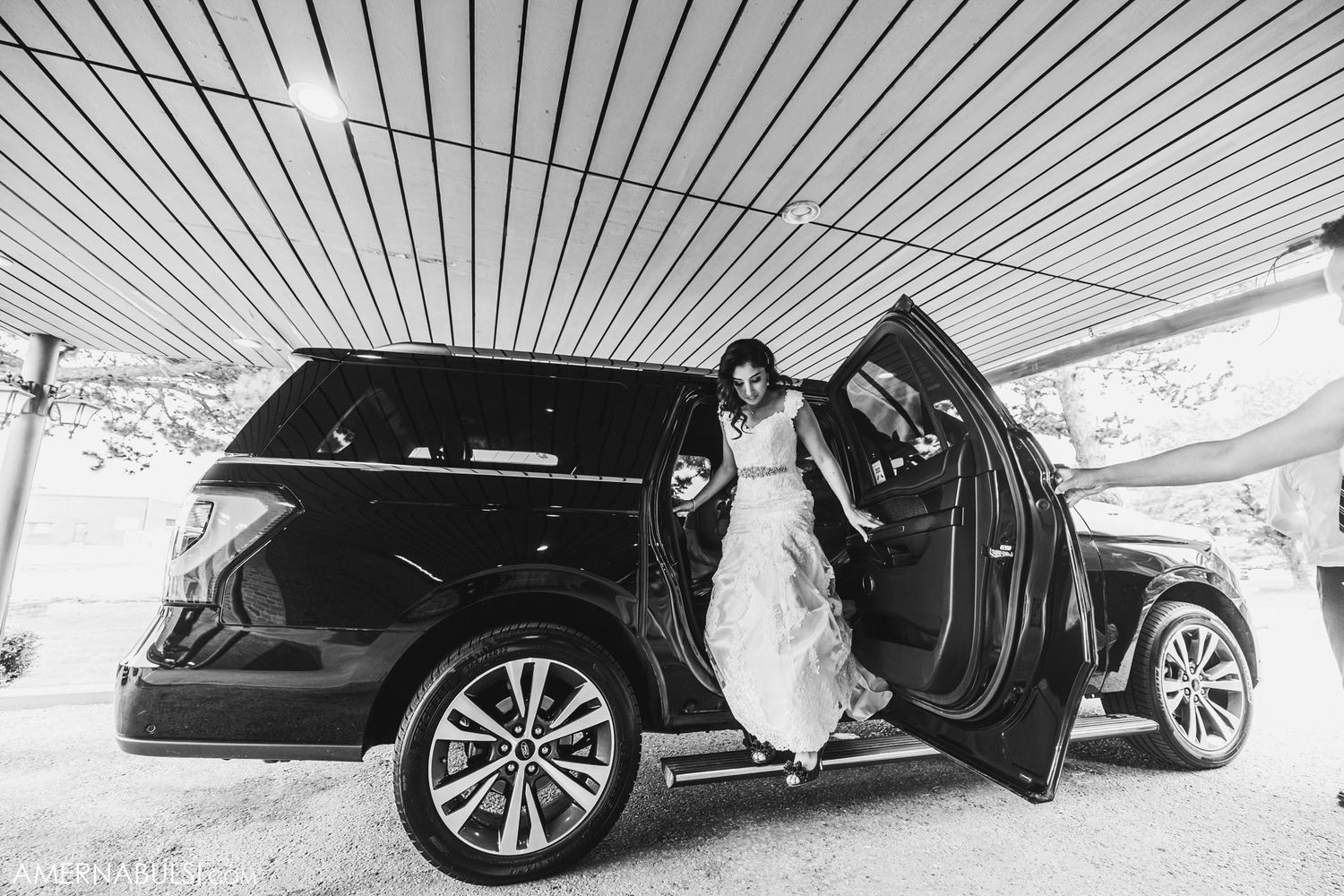 Black luxury SUV with open door at a formal event under covered area.
