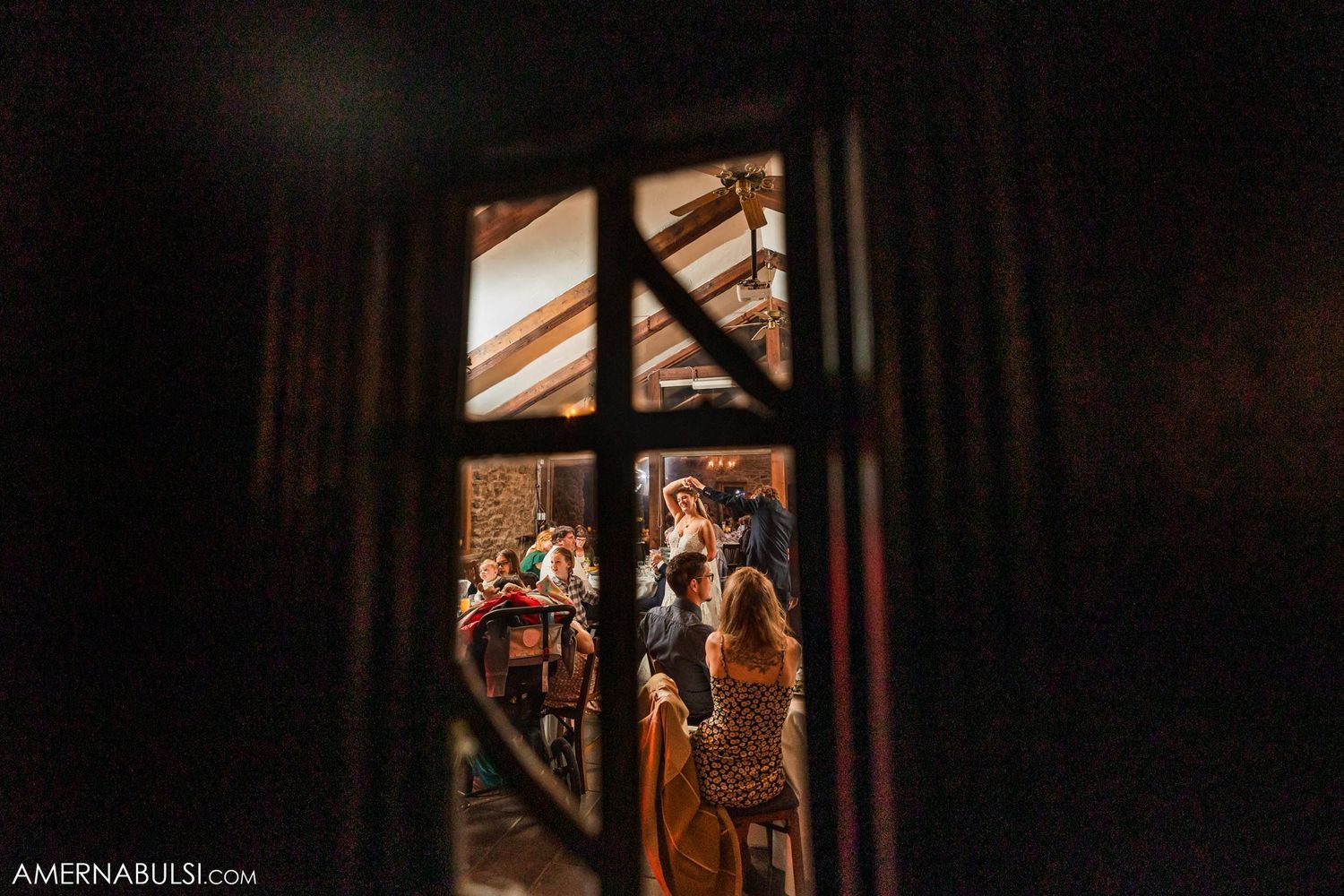 A romantic wedding moment captured through a vintage window frame in the evening.