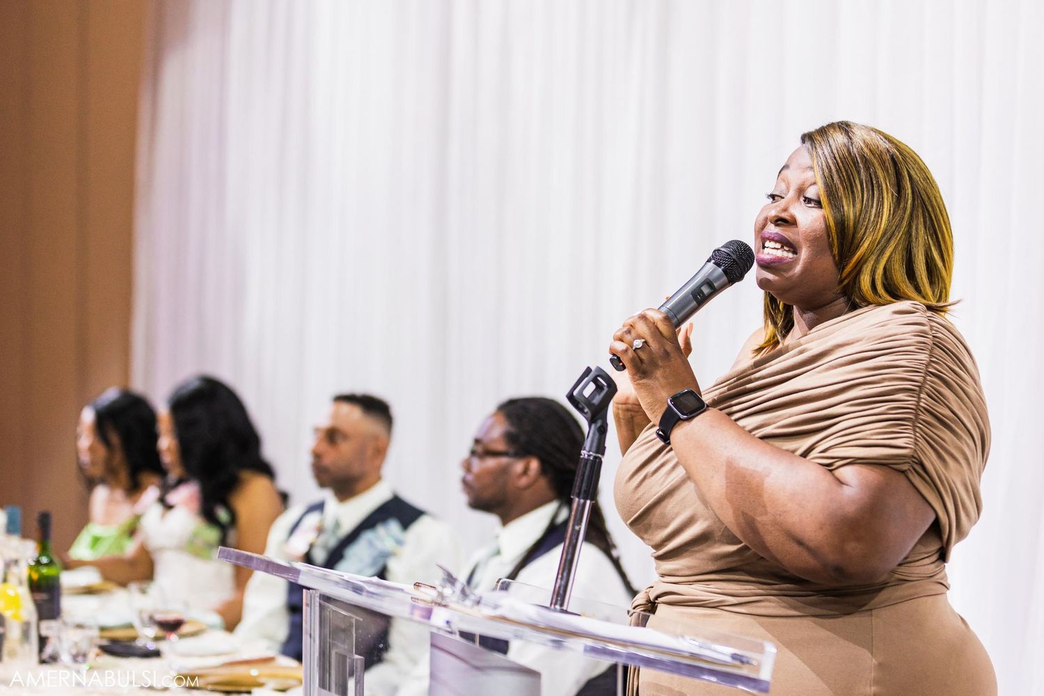 Wedding guest delivers passionate speech while holding microphone at reception celebration.