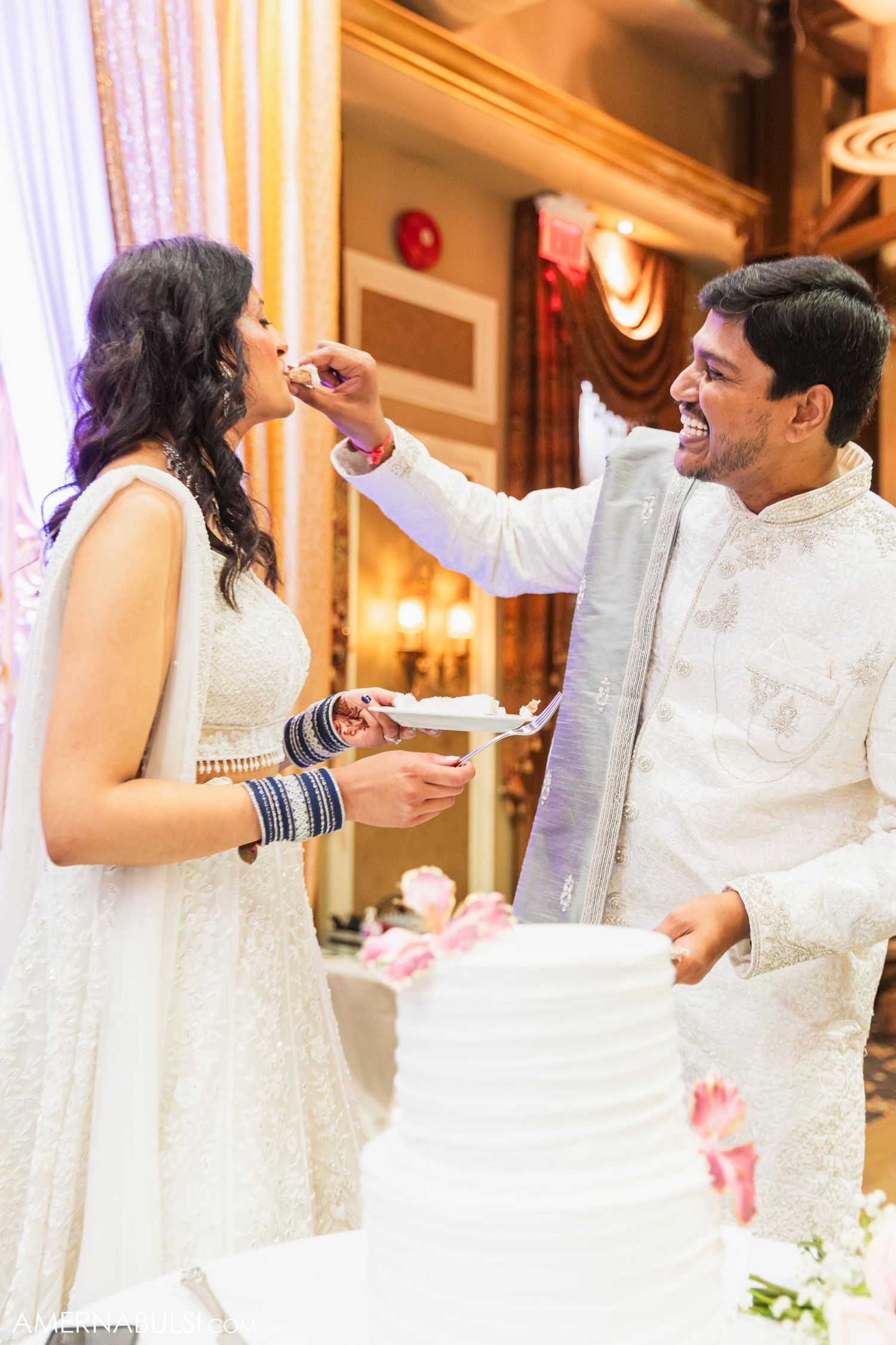 Wedding couple shares a playful cake-feeding moment during their reception celebration.