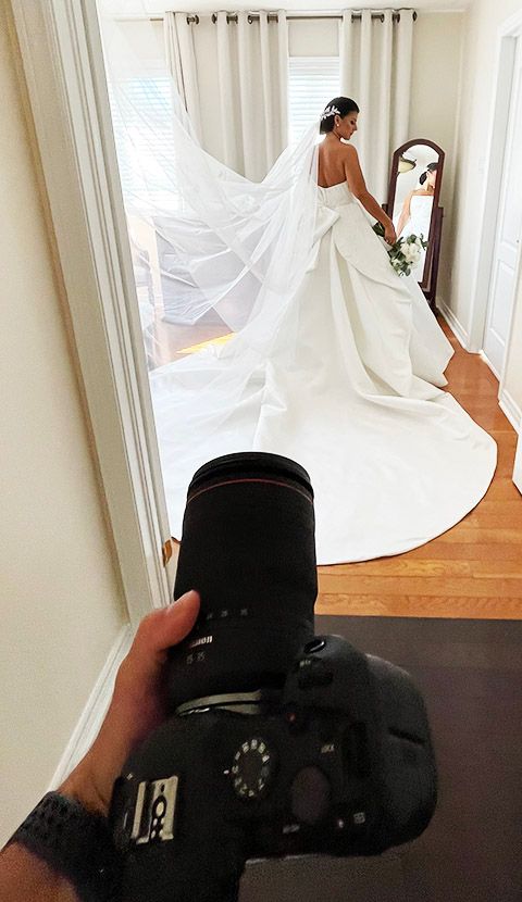 Wedding photographer crouching to capture creative angles of bride in flowing white dress.
