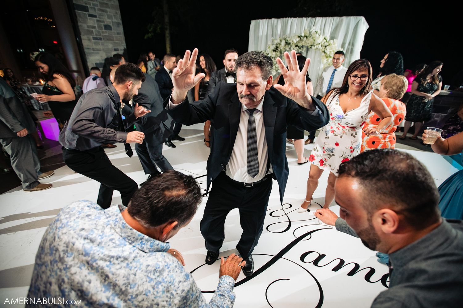 Wedding reception dance floor with guests celebrating on black and white checkered floor.