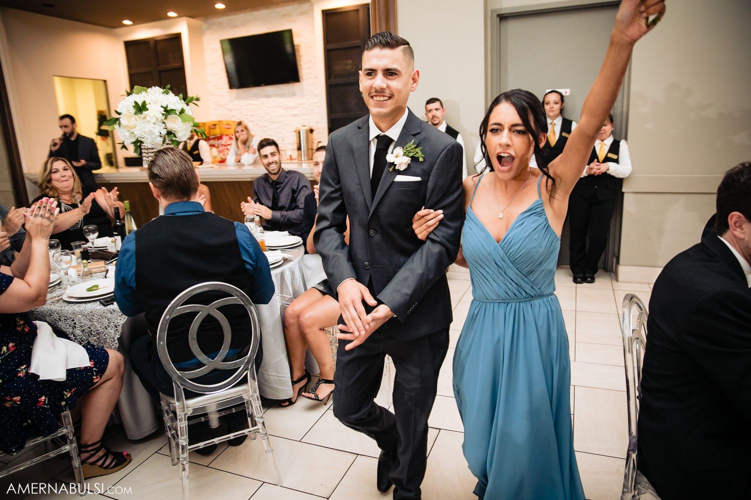 Wedding reception celebration with guests in formal attire and blue bridesmaid dress.