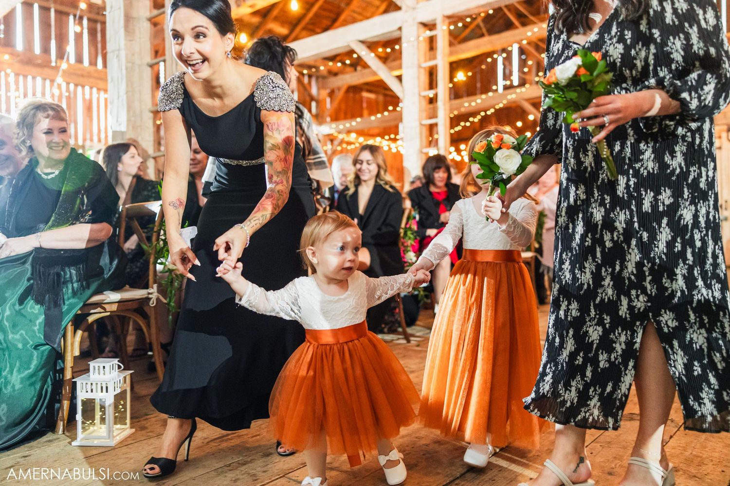 Dancing celebration on wooden floor of rustic barn with string lights and festive atmosphere.