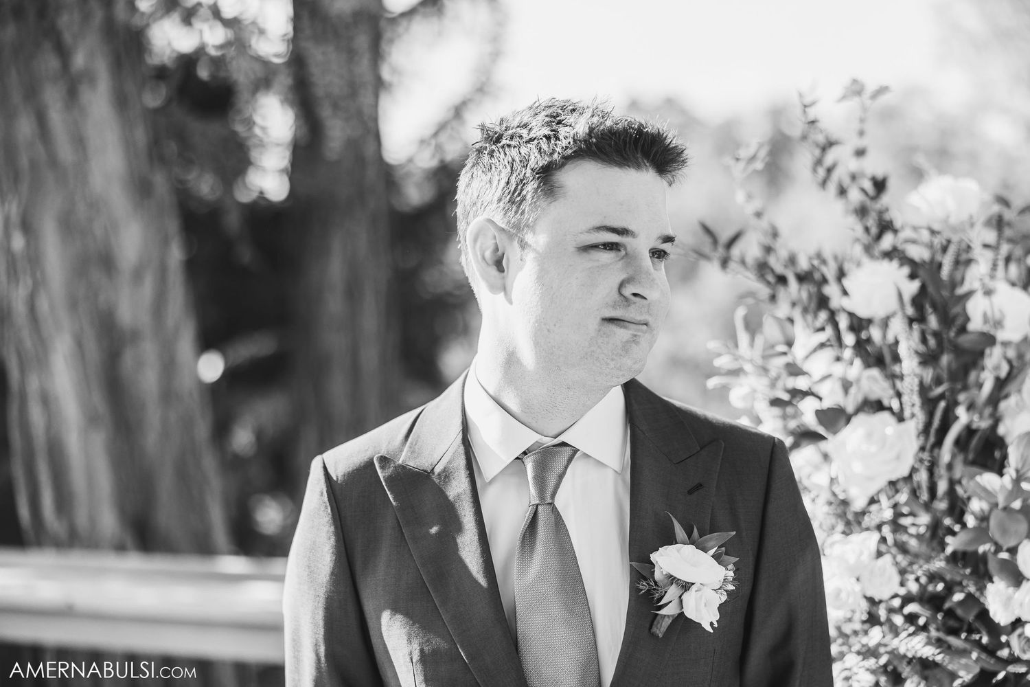 Natural outdoor portrait of a groom wearing a navy suit and tie with a boutonniere.