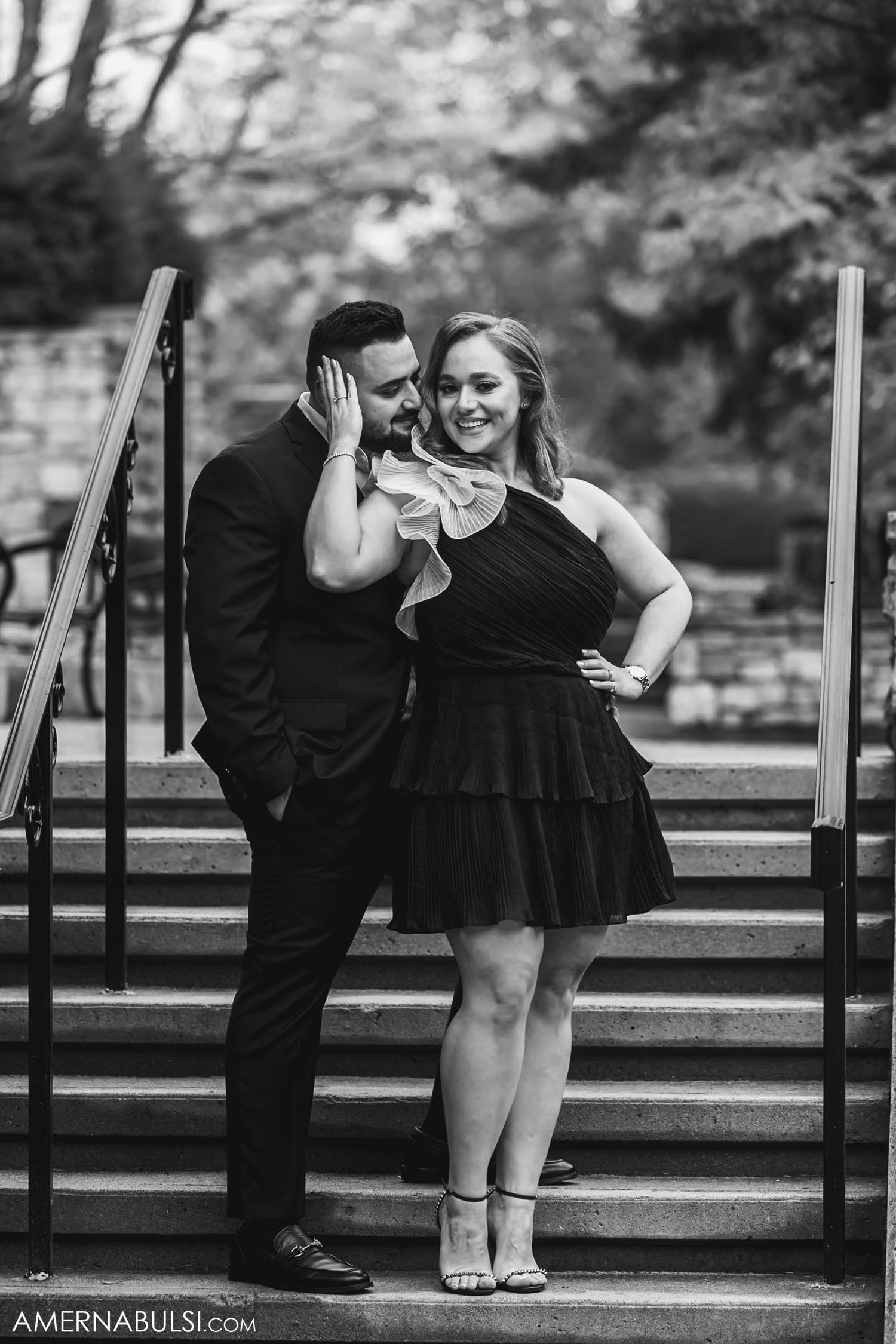 Black and white portrait of couple posing playfully on stone staircase.