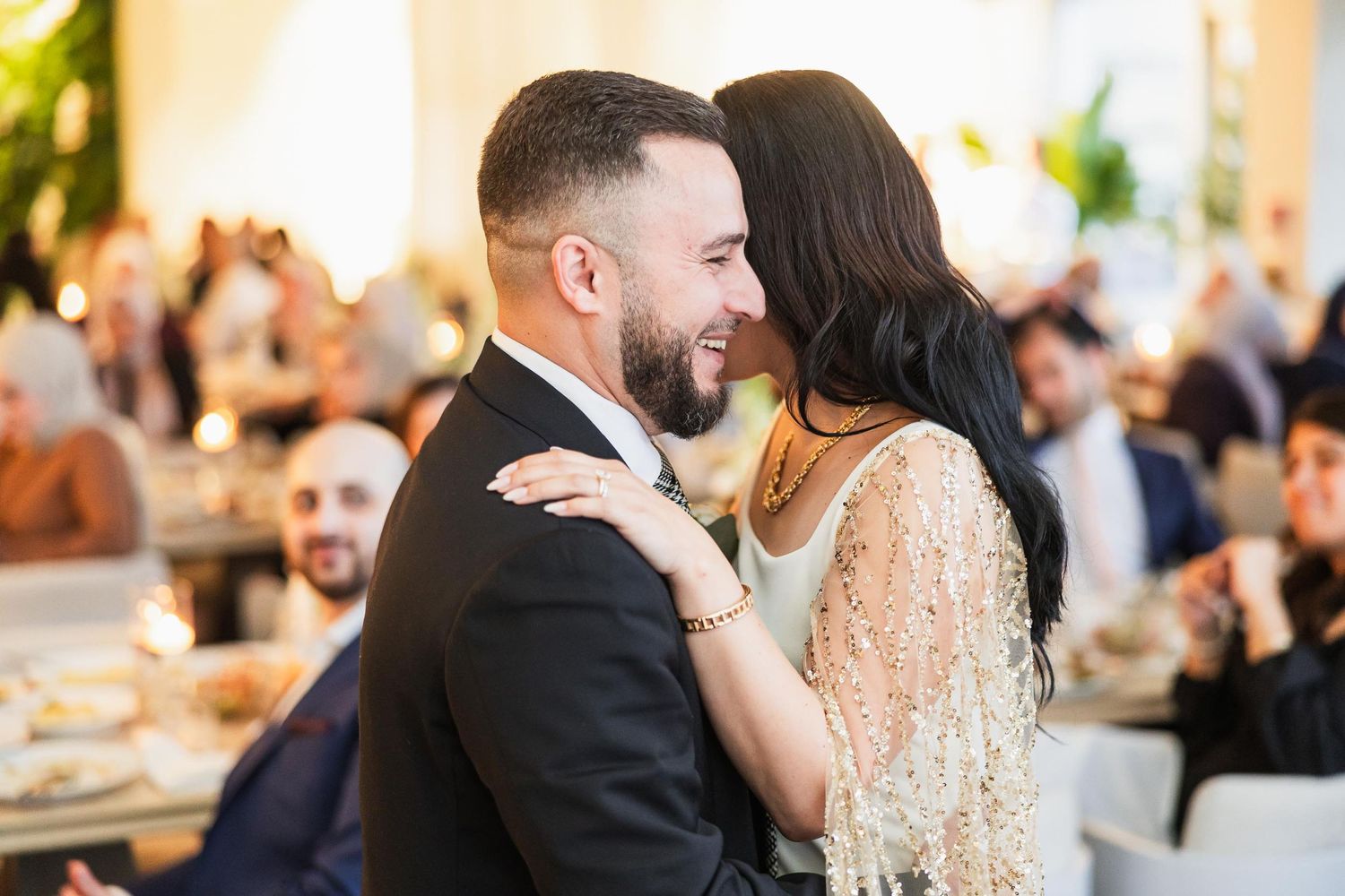 A tender moment between newlyweds during their wedding reception in an elegantly lit venue.