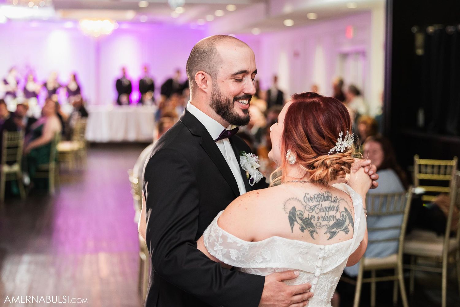 Couple sharing intimate dance moment at reception with purple ambient lighting.