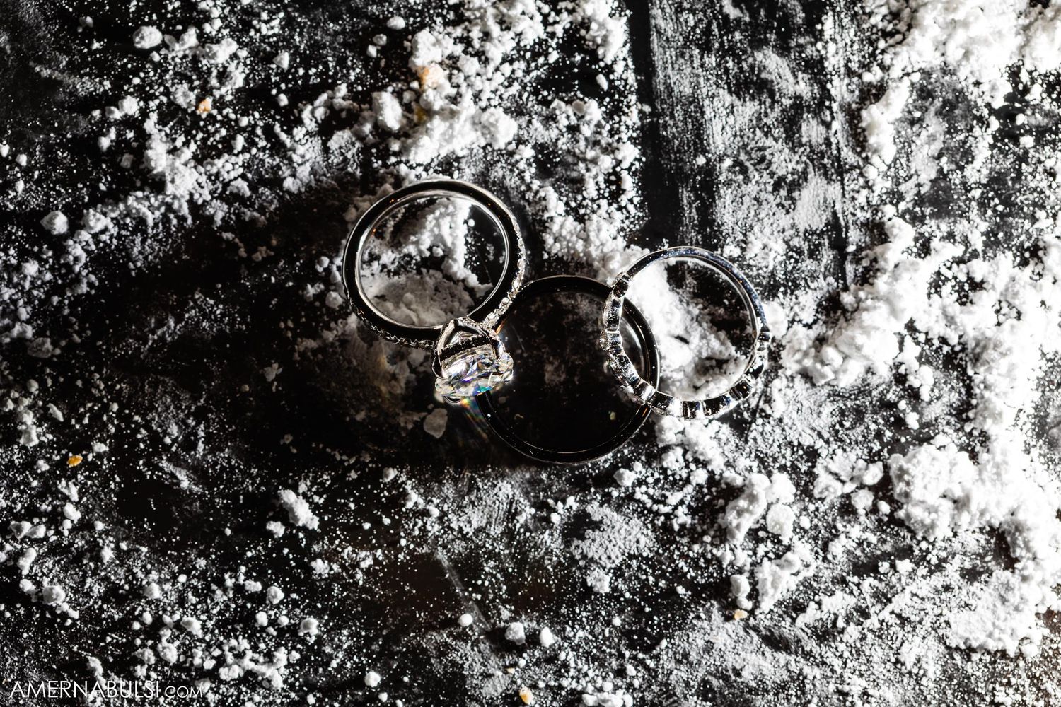Wedding rings photographed in dramatic black and white on a textured surface.