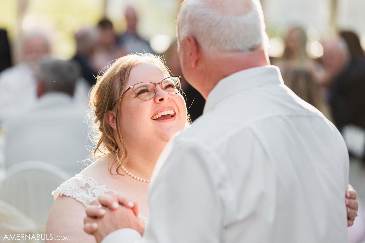 Two people share a joyful dance moment at an indoor wedding celebration.