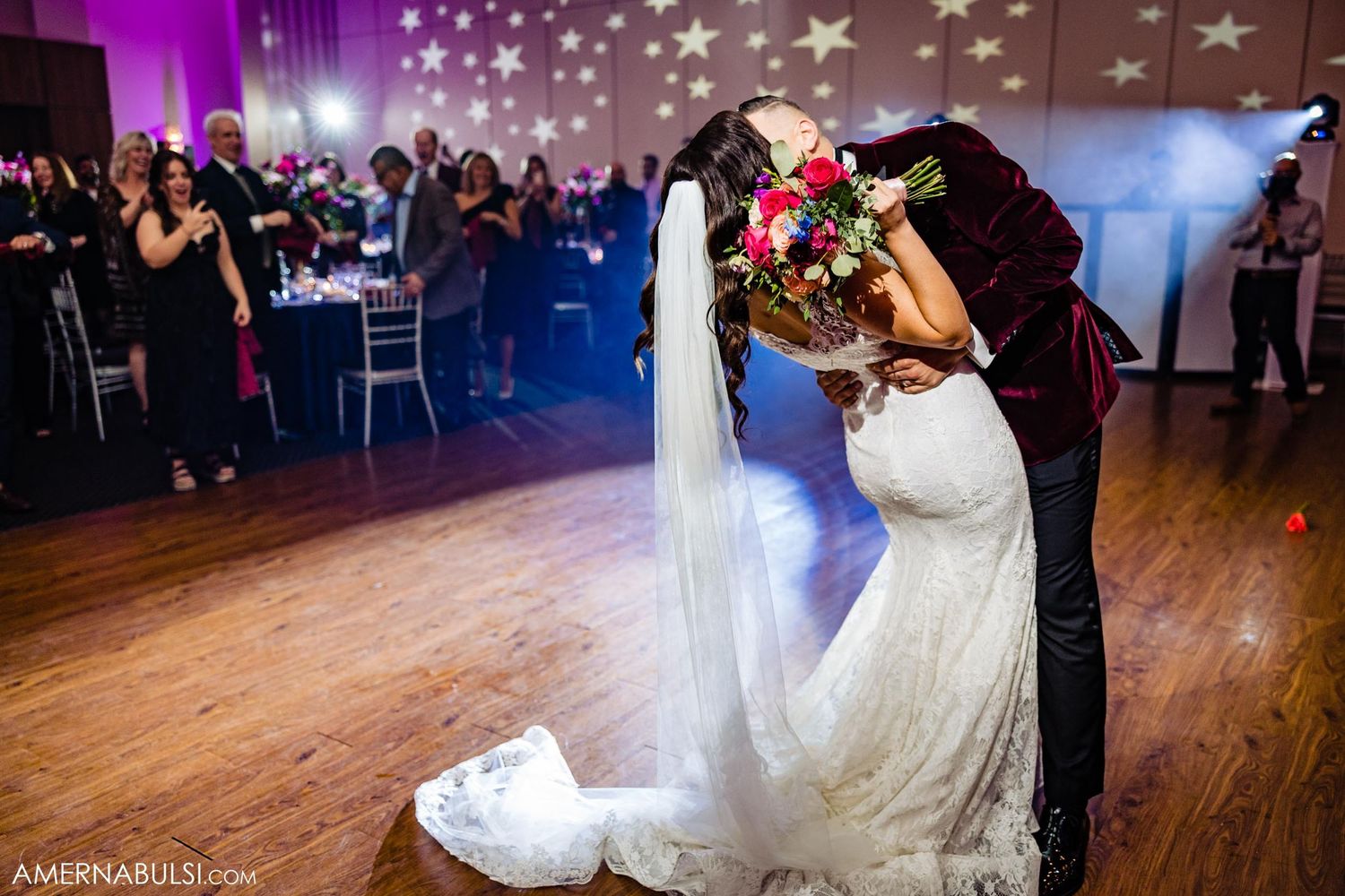 Couple sharing a romantic first dance moment under twinkling star decorations and pink lighting.