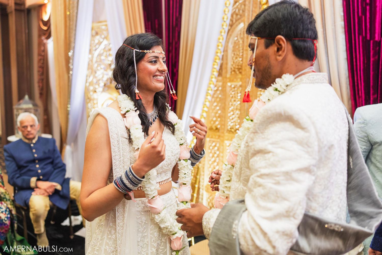 Wedding ceremony exchange between couple with elegant curtained backdrop and decorative setting.