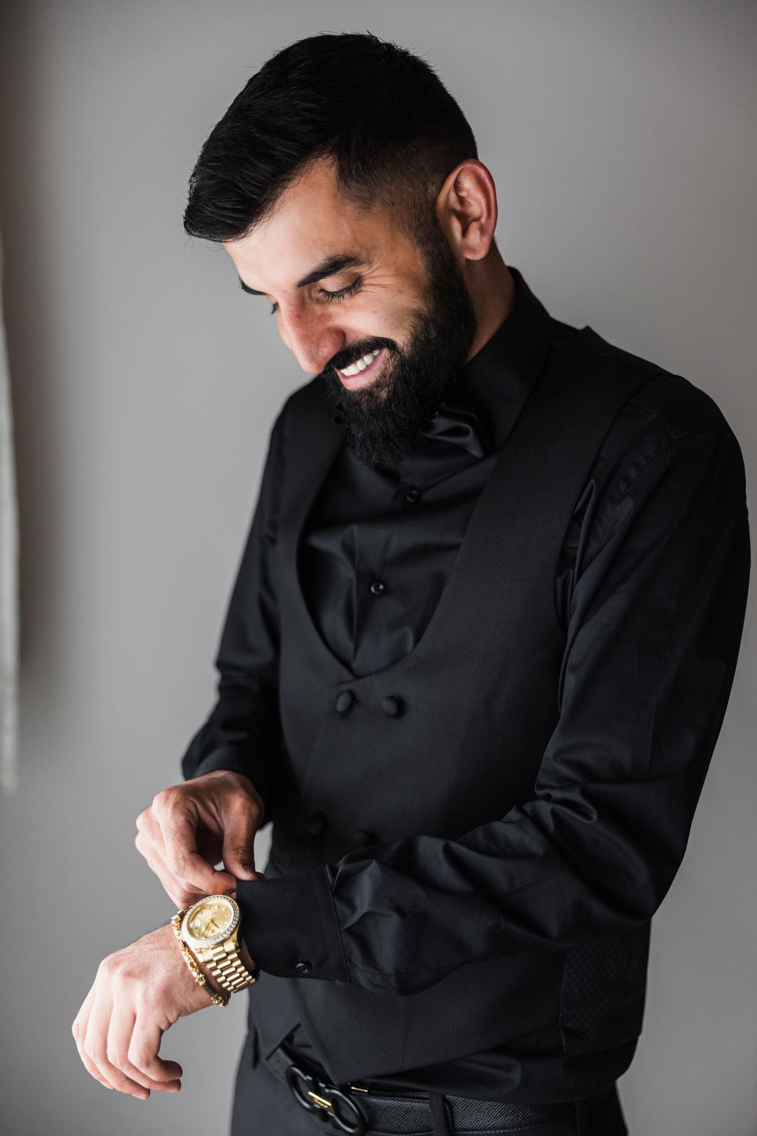 Candid moment of joy captured in elegant black formal wear with gold watch detail.
