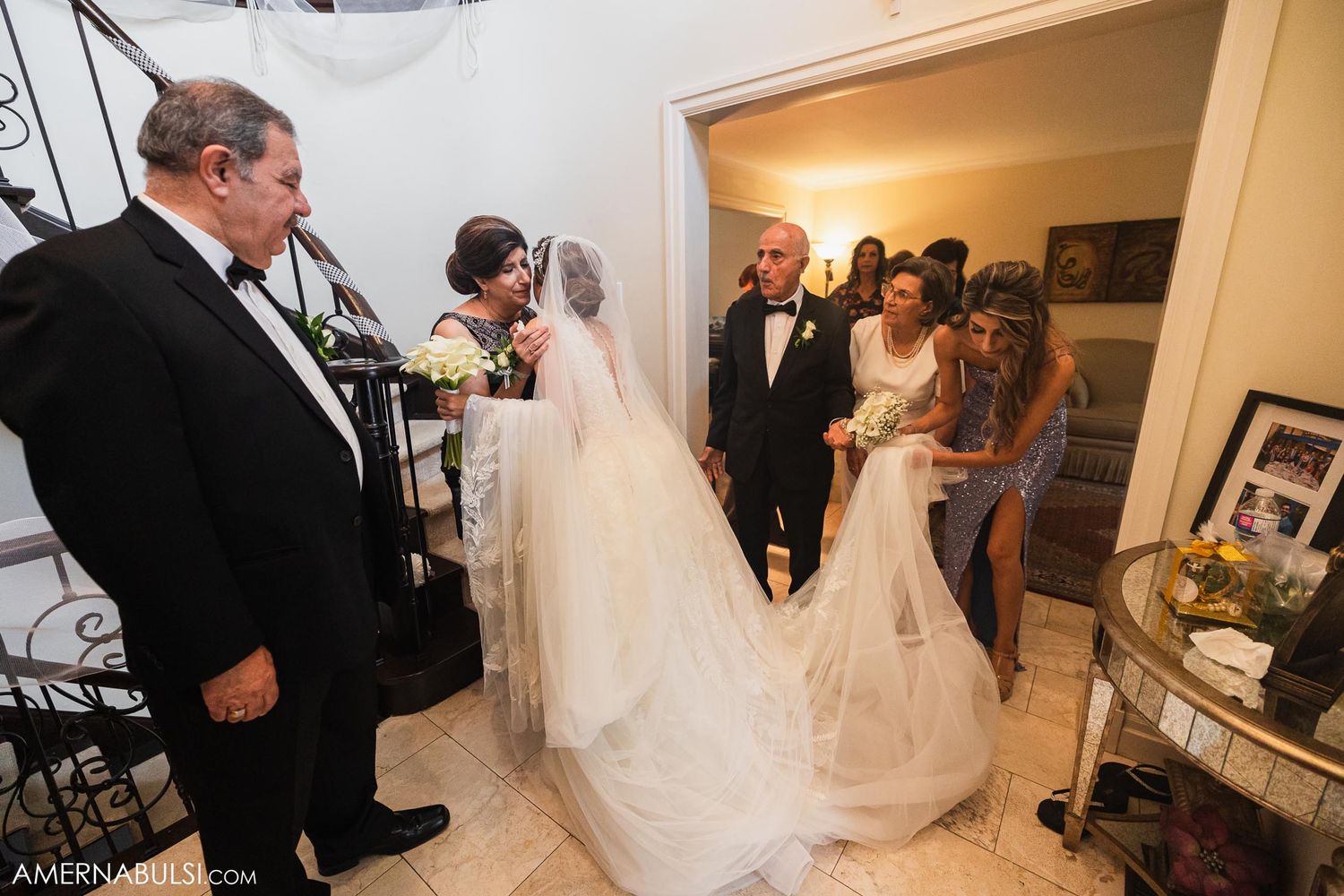 Wedding processional moment captured in elegant hallway with decorative staircase.