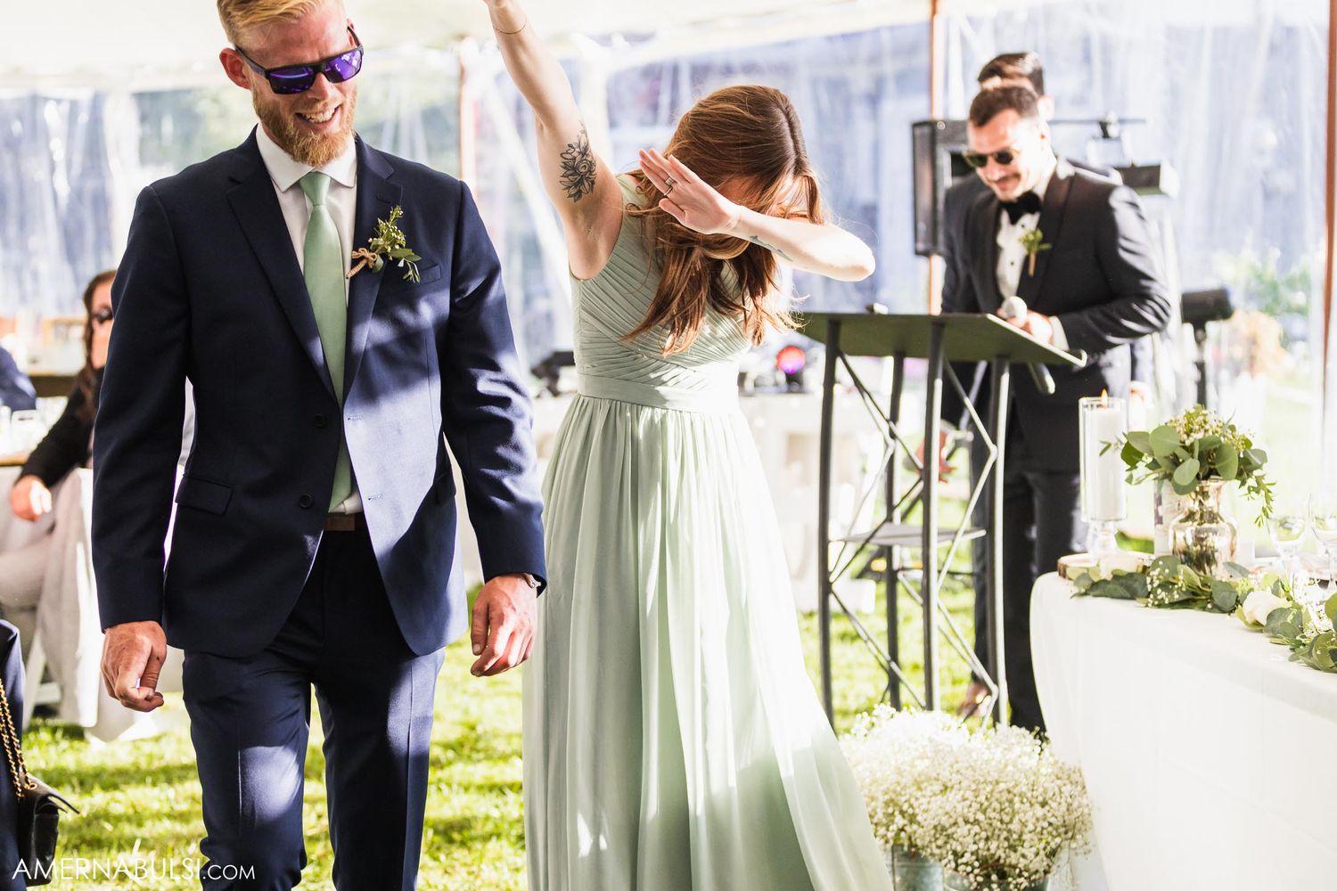 Celebratory dance moment under a white tent at an outdoor wedding reception.