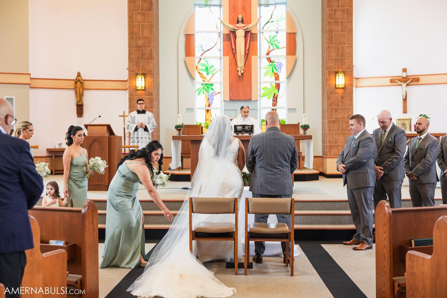 A traditional church wedding ceremony taking place at the altar with wooden pews and stained glass windows.