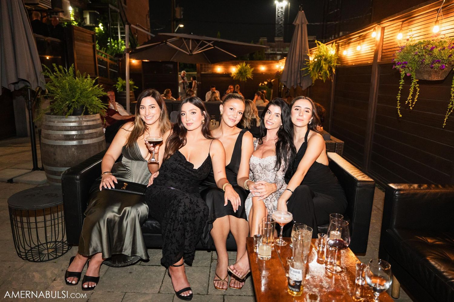 A group poses together on an outdoor patio decorated with string lights during an evening celebration.