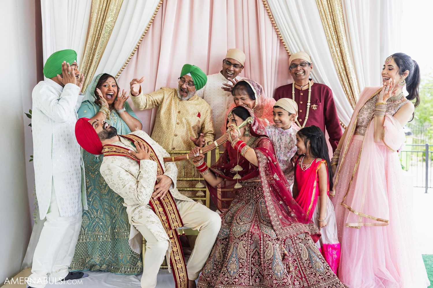 Joyful Sikh wedding party posing together in traditional ceremonial attire.